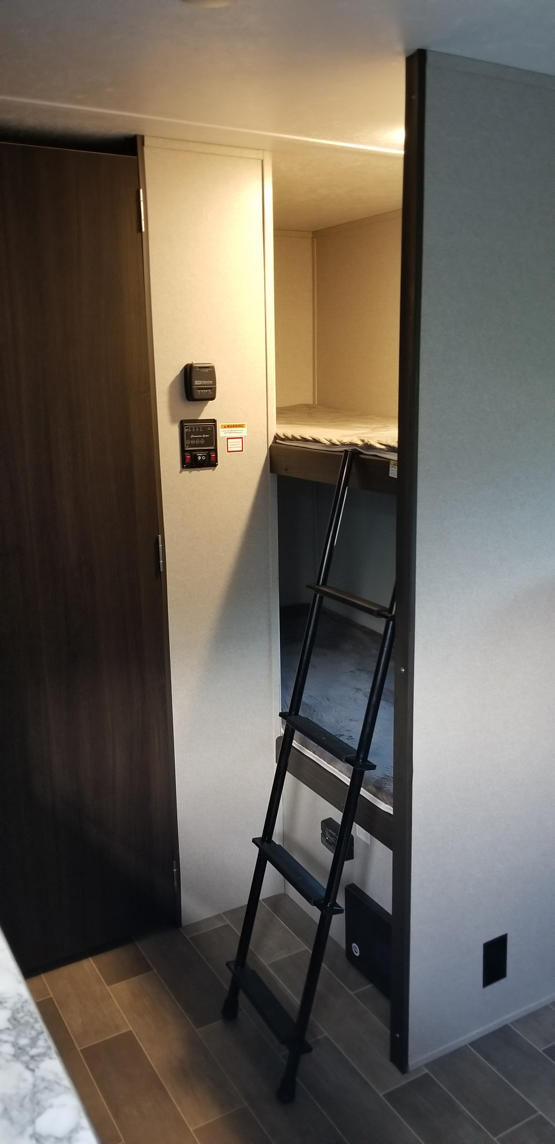 Experience comfort in this RV rental featuring a bunk bed setup with a ladder, wall controls, and stylish wood-look flooring.. Keystone Springdale 2019