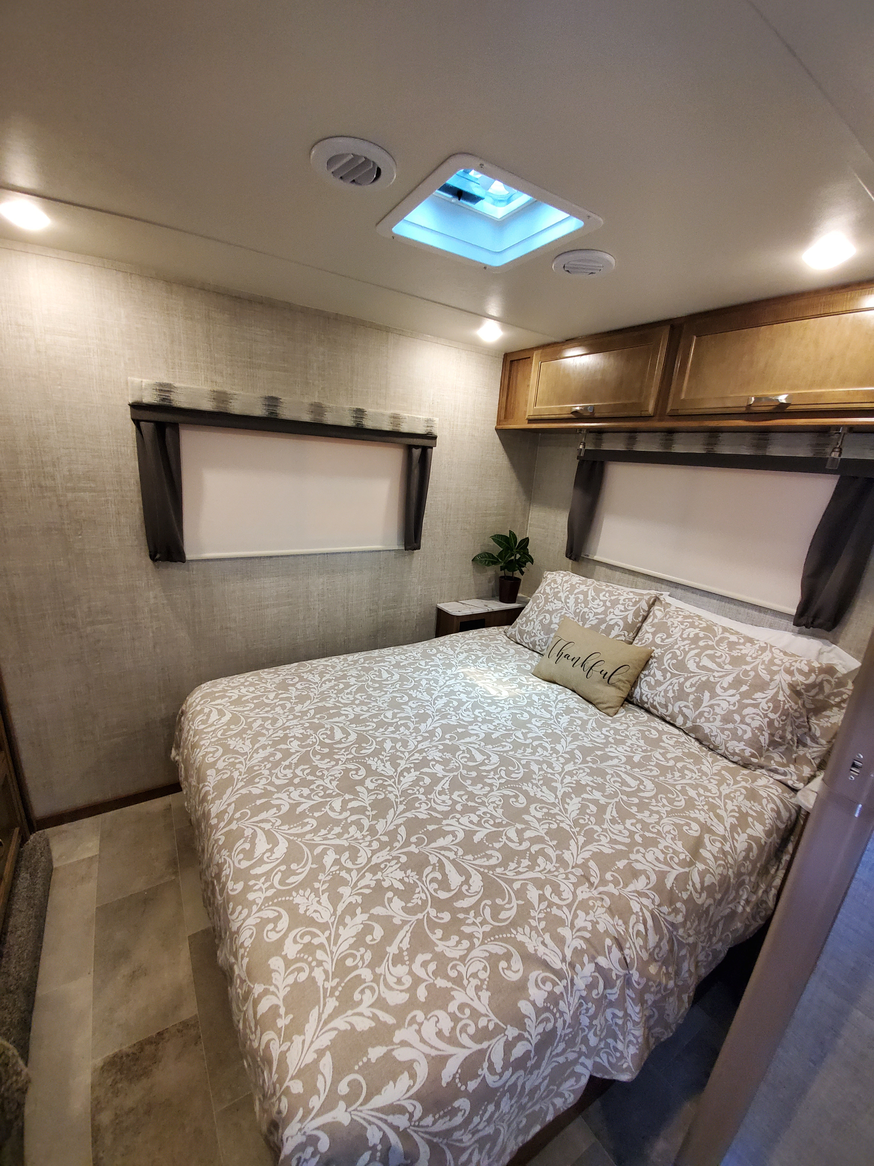 Inviting RV rental bedroom: patterned bed, overhead cabinets, and a bright skylight create a cozy travel space.. Gulf Stream Conquest 2020