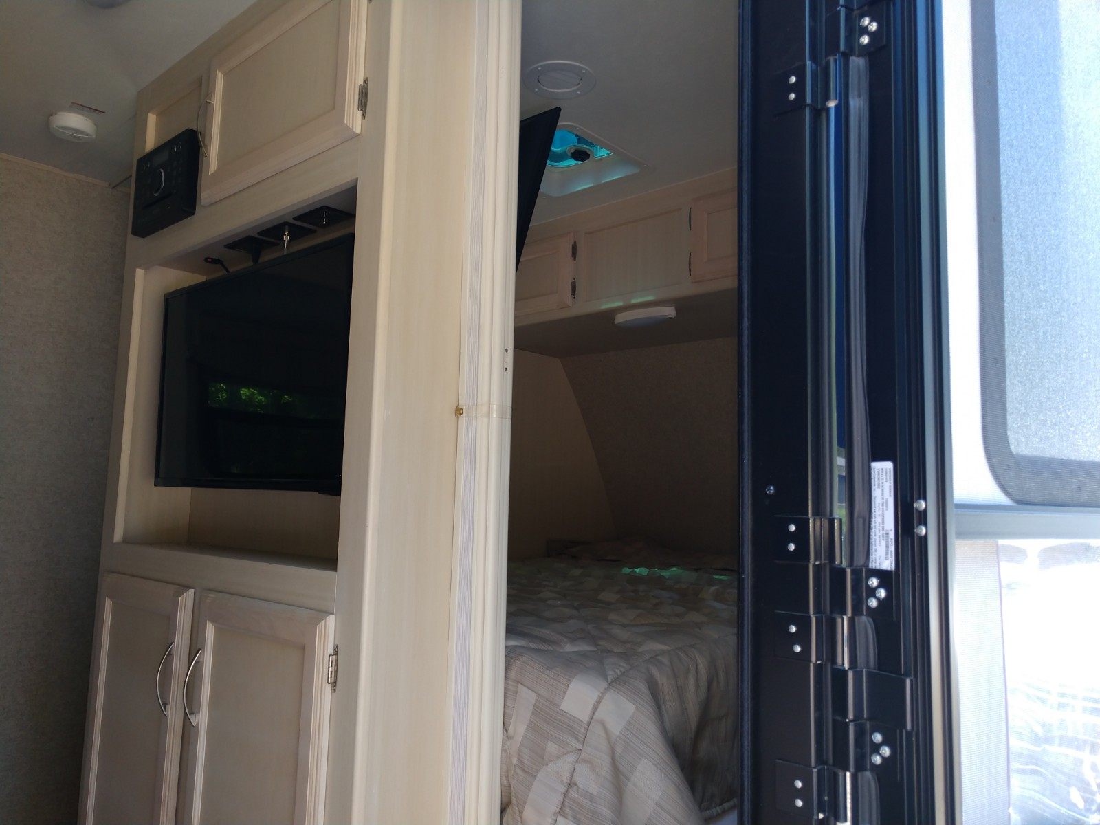 Inside this RV rental: A compact living space with TV and a comfy bedroom visible through the doorway.. Other Minnie Winnie 2018