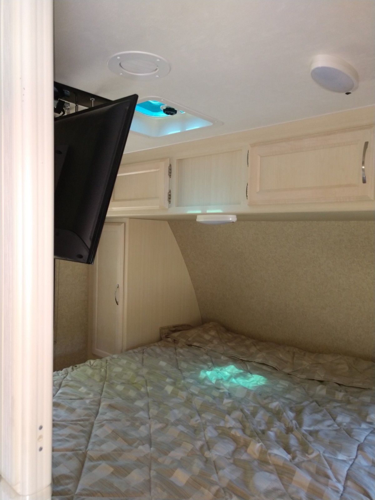 Inside an RV rental: a compact bedroom with mounted TV, ceiling skylight, storage cabinets, and a comfy bed.. Other Minnie Winnie 2018