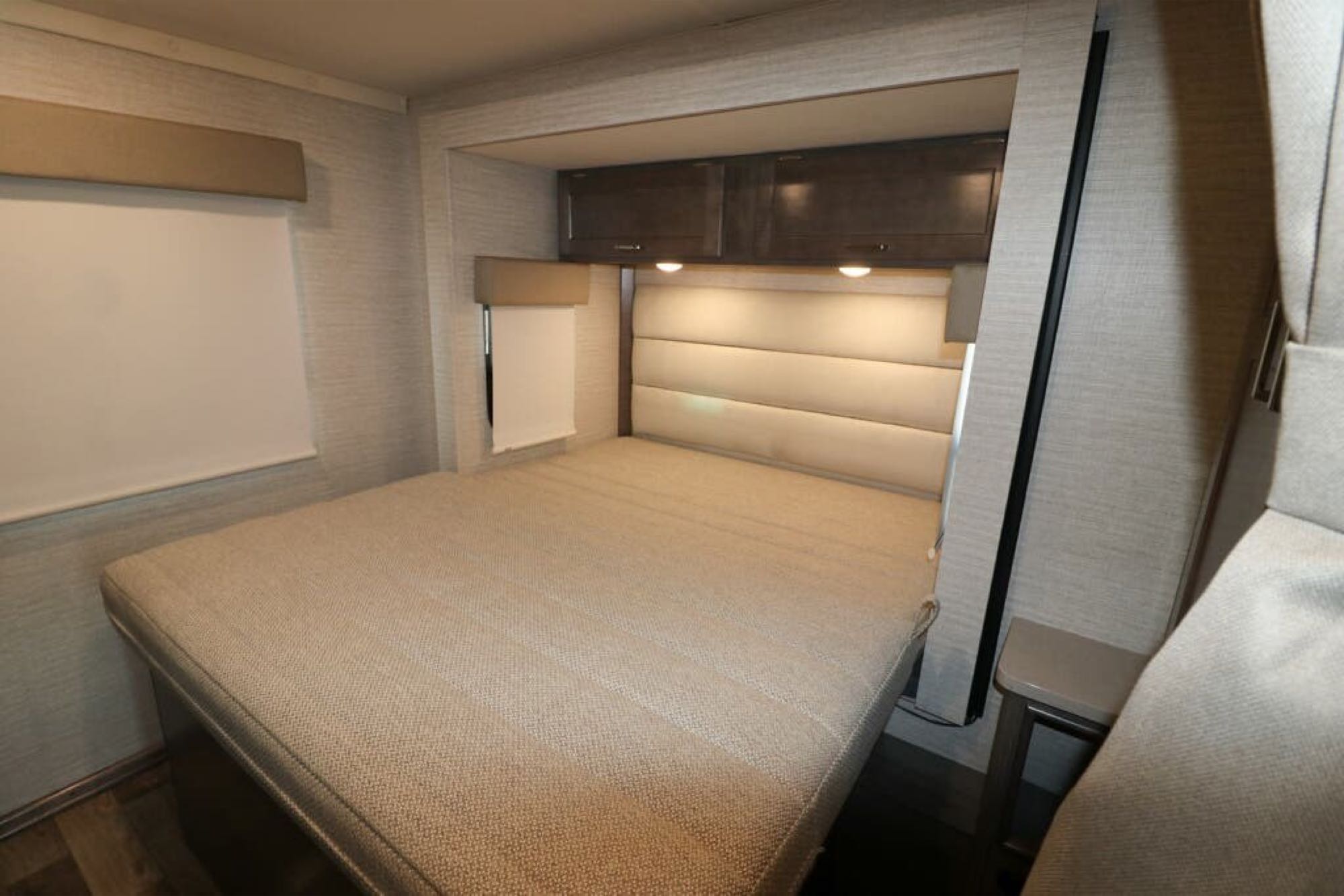 Cozy RV rental bedroom with padded headboard, overhead cabinets & window blinds. Perfect for travel.. Winnebago Spirit 2020