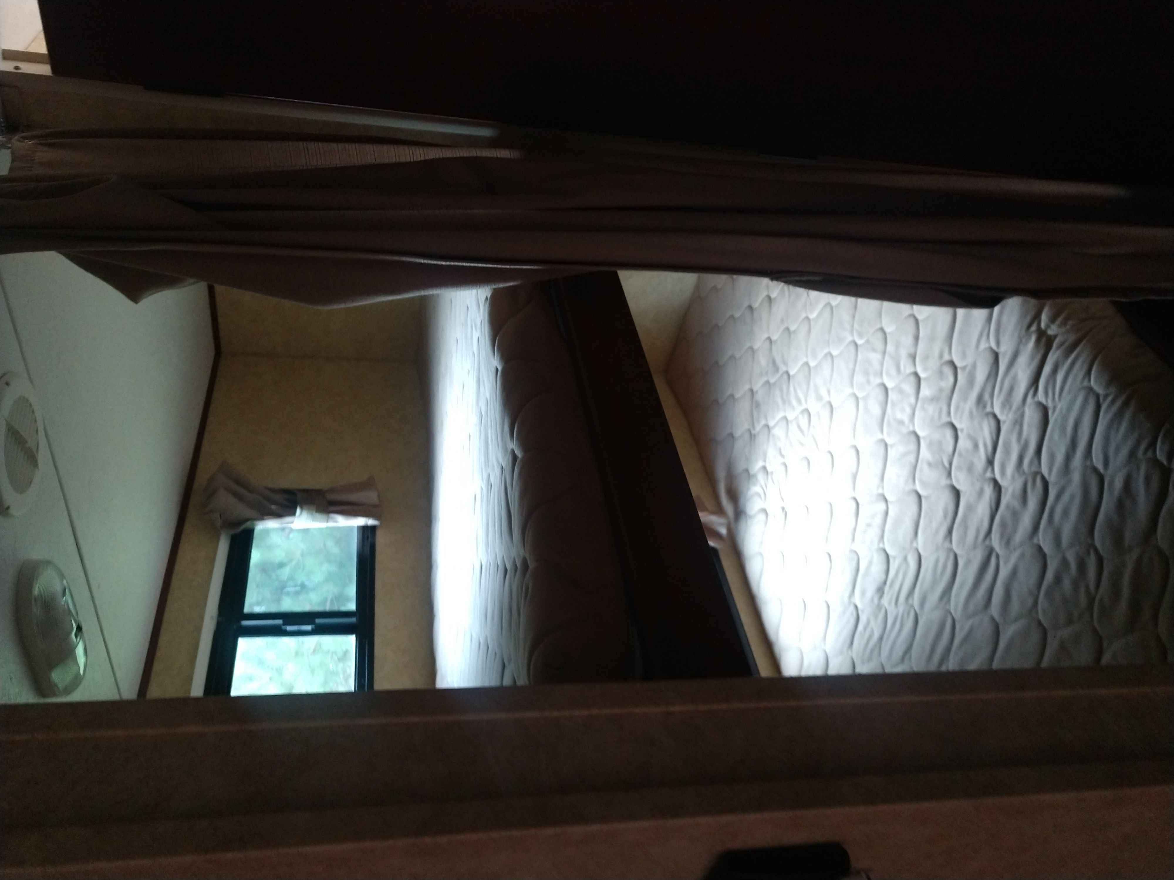 Cozy sleeping area in an RV rental: Two quilted bunk mattresses are visible, with a window and vent nearby.. Avenger Avenger Trailer 2013