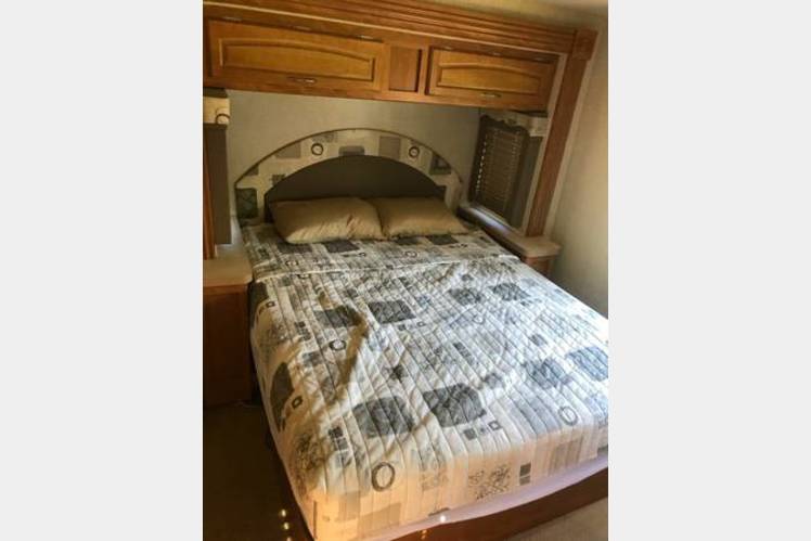 Spacious RV rental bedroom featuring a full bed, overhead cabinets, and built-in storage.. Fleetwood Jamboree 2007