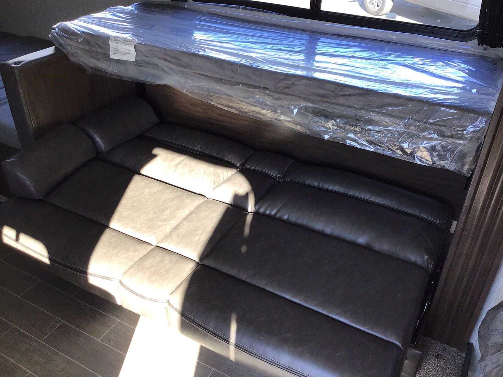 RV rental interior: new bunk bed (plastic-wrapped) above a dark, comfortable sofa, perfect for travel.. Forest River Cherokee Wolf Pup 2020