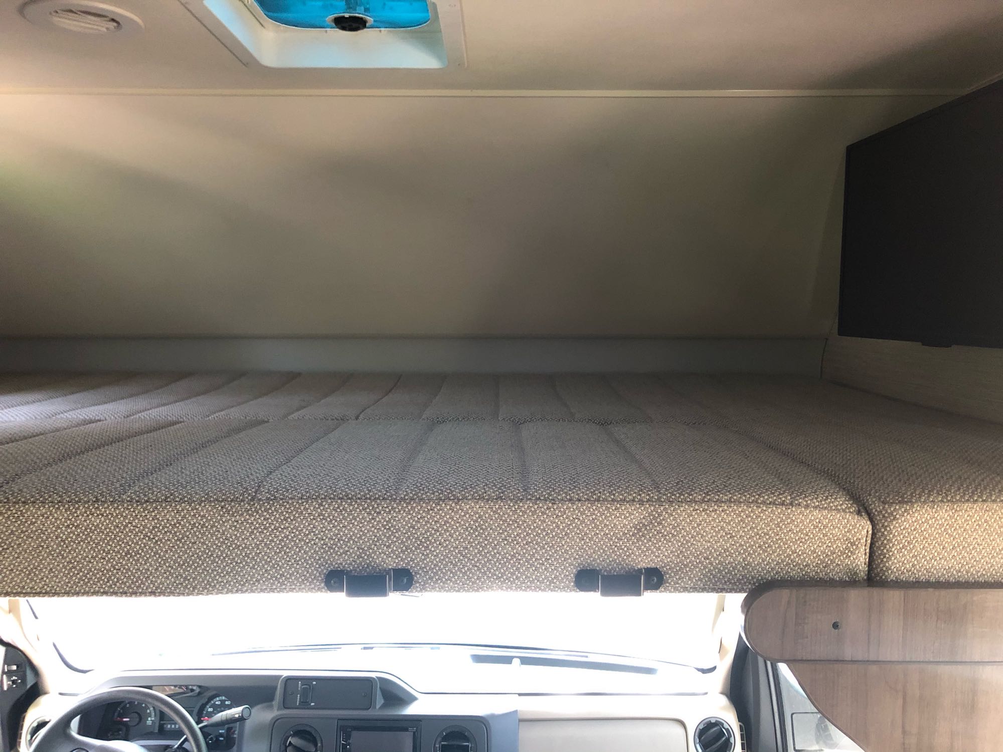 Overhead bunk bed in an RV rental, featuring a textured mattress and comfortable sleep area above the cab.. Winnebago Spirit 2020