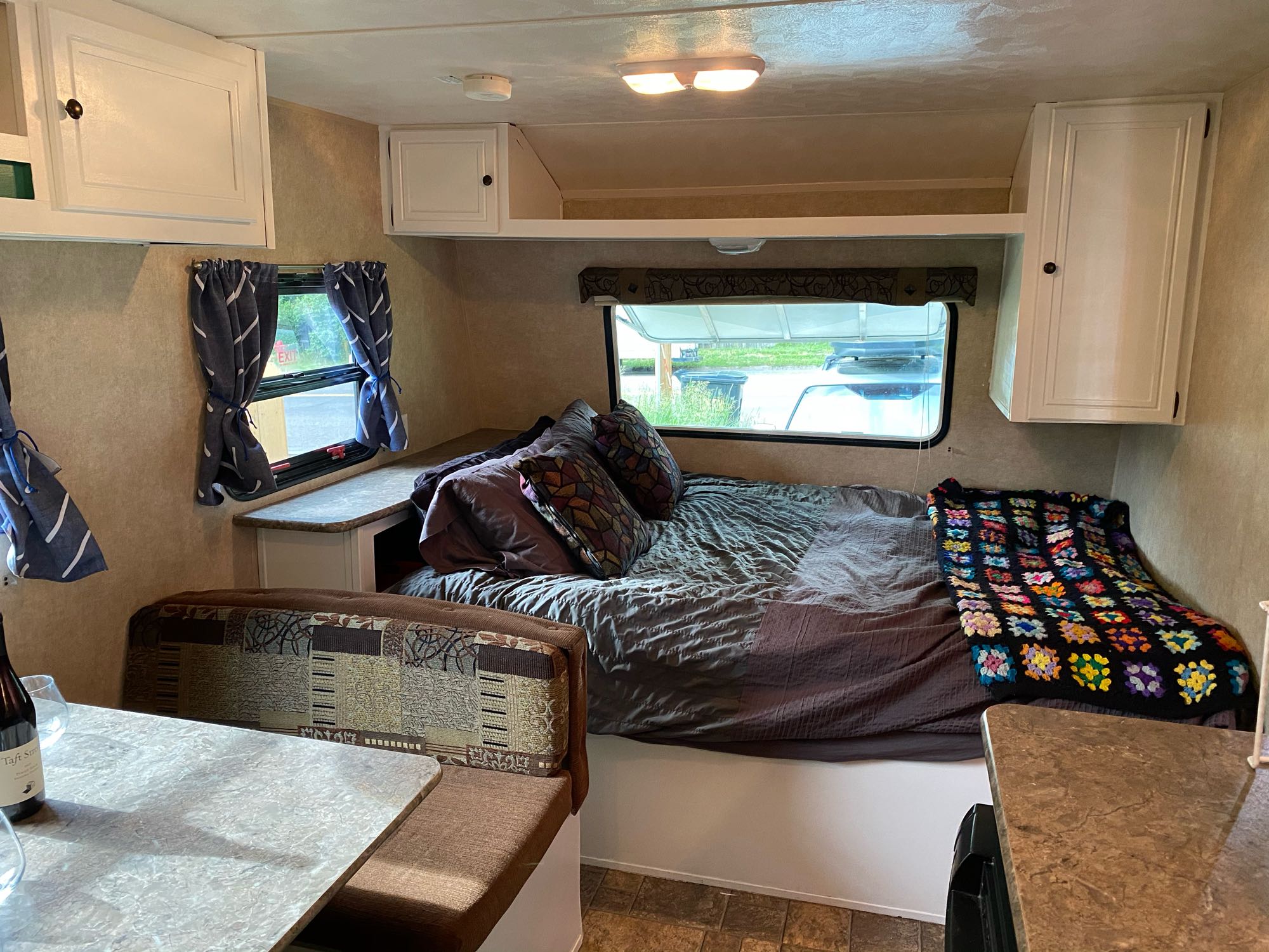 Cozy RV rental interior featuring a comfortable bed, overhead cabinets, and a dinette for a compact living space.. Palomino Canyon Cat 2014