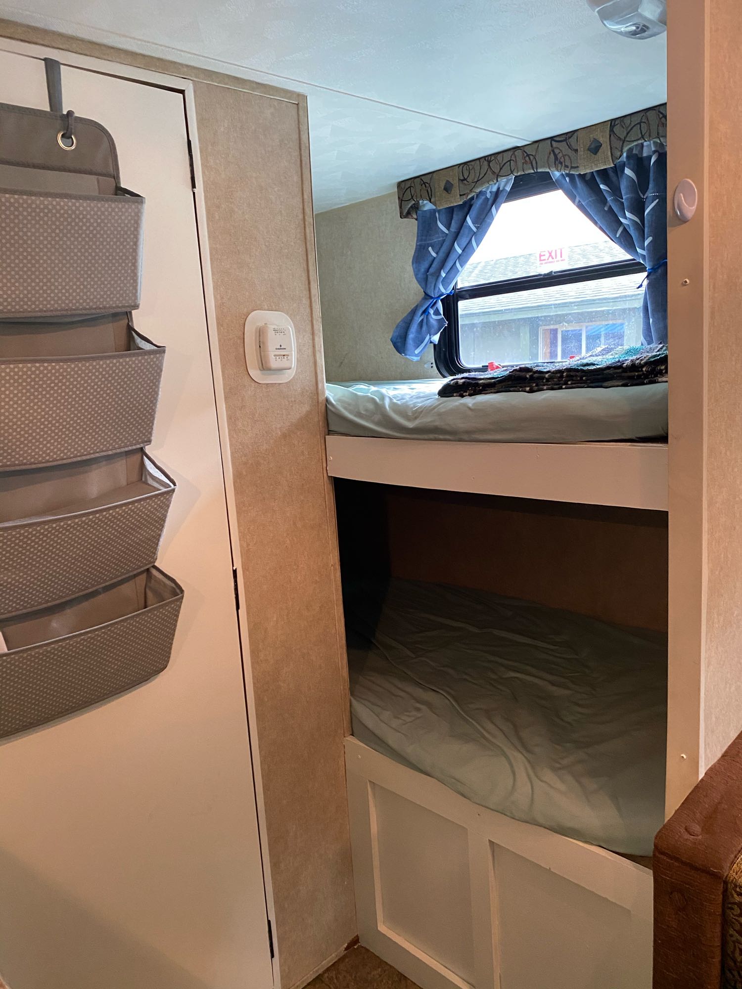 RV rental interior: Bunk beds with window curtains, hanging door storage, and thermostat visible for a comfortable camper trip.. Palomino Canyon Cat 2014