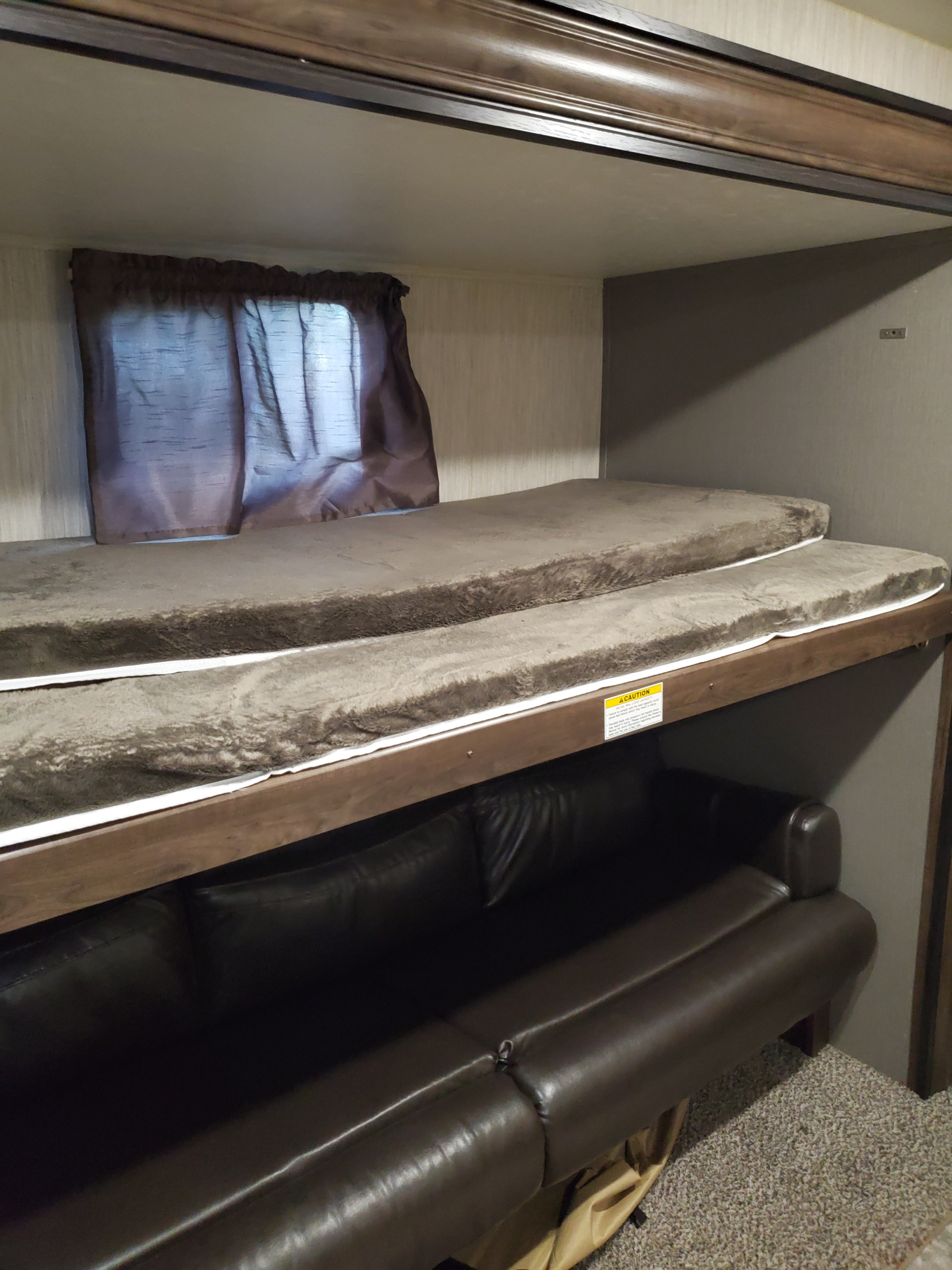 RV rental interior: stacked bunk beds with plush grey mattresses and a dark brown sofa below.. Other Other 2019