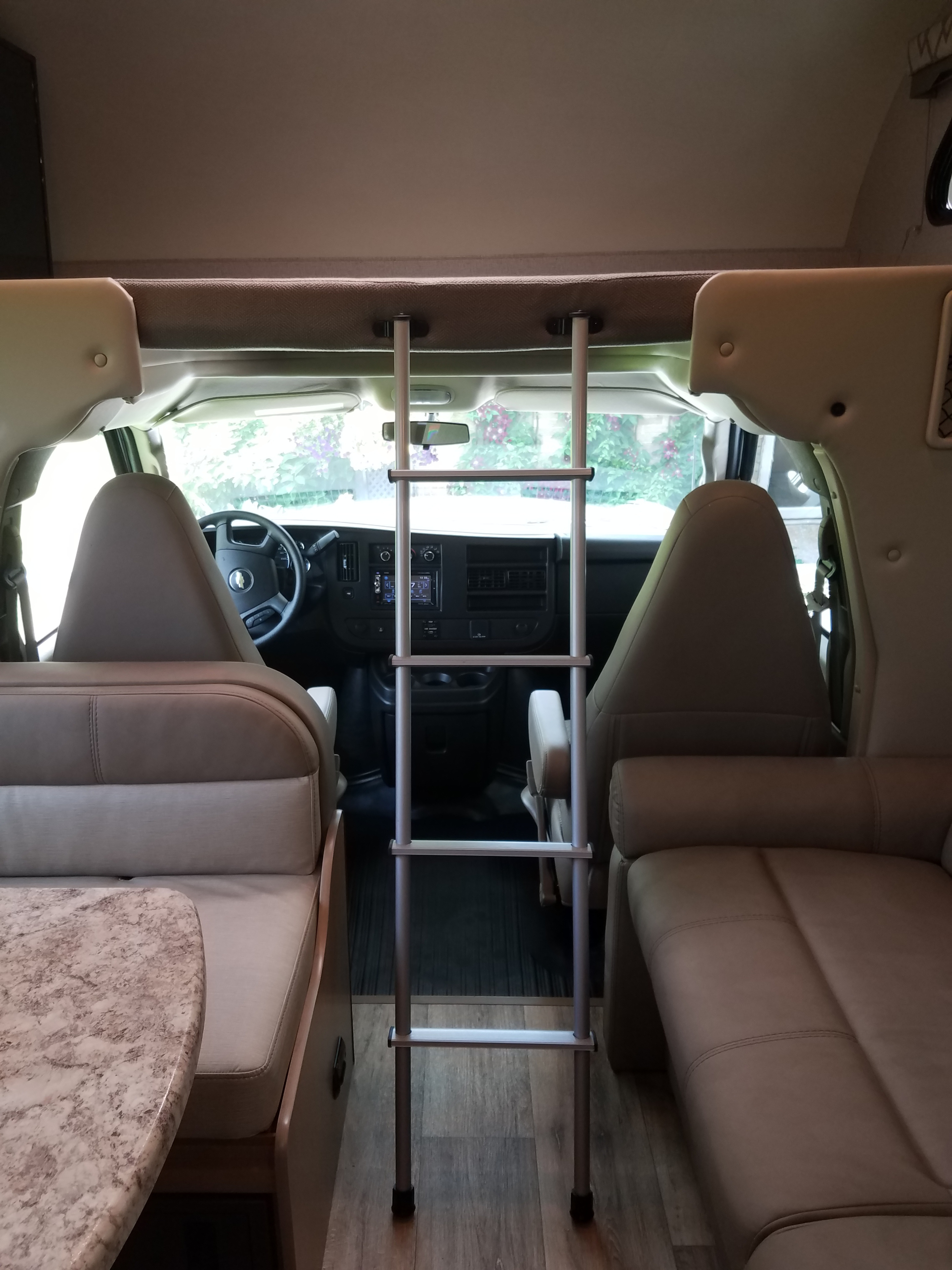 Experience comfort in this RV rental interior, featuring an overhead bunk ladder, driver's cabin, dinette, and sofa.. Thor Four Winds 2020