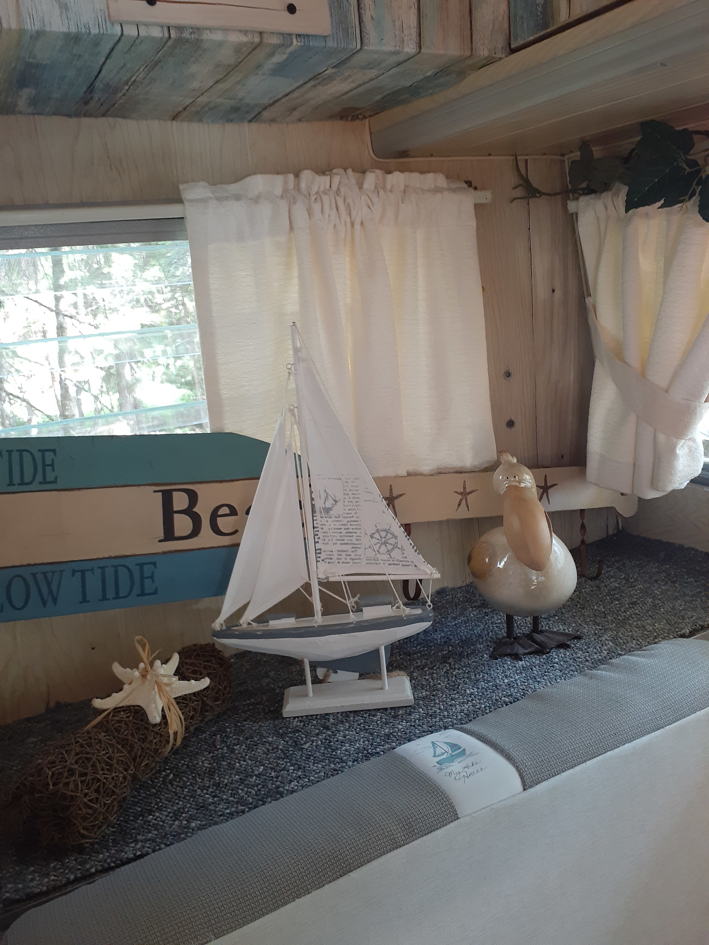 Cozy RV rental interior with beach-themed decor: sailboat, pelican, and starfish accents.. Aristocrat Lo-Liner 1965