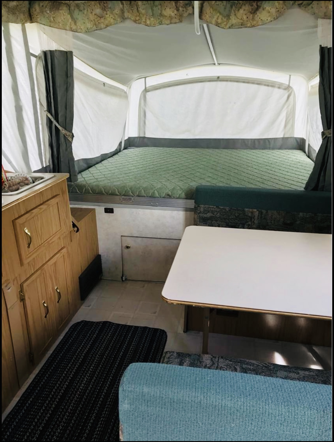 Spacious pop-up camper interior, featuring a bed, dinette, and sink area. Ideal for your next rv rental adventure.. Coleman GrandTourMesa 1999