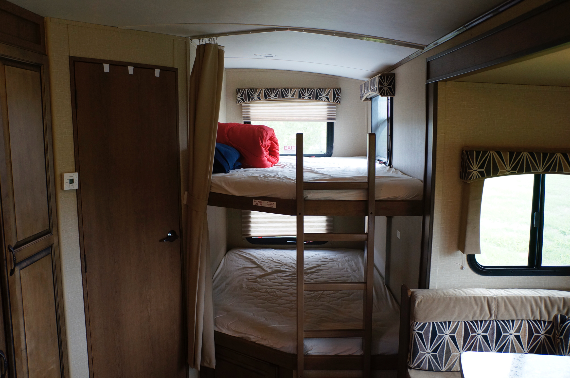 Cozy RV rental interior showing bunk beds with a ladder, a red sleeping bag, and dinette seating.. Cruiser RV Viewfinder Signature VS-28BHSS 2014