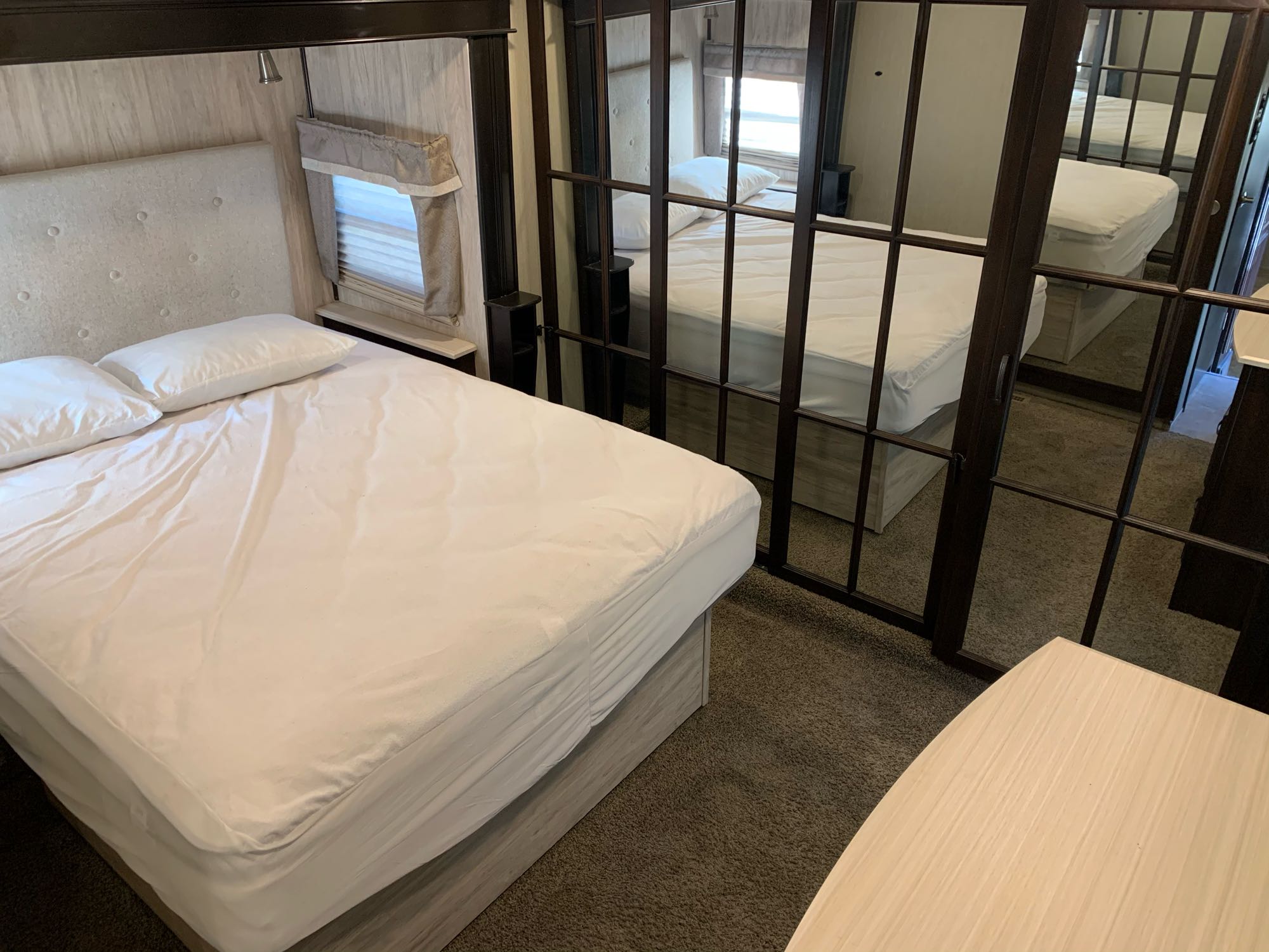 Bright RV rental bedroom showcasing a clean, comfortable bed with white linens, a window, and mirrored closet doors.. Palomino Columbus 2018