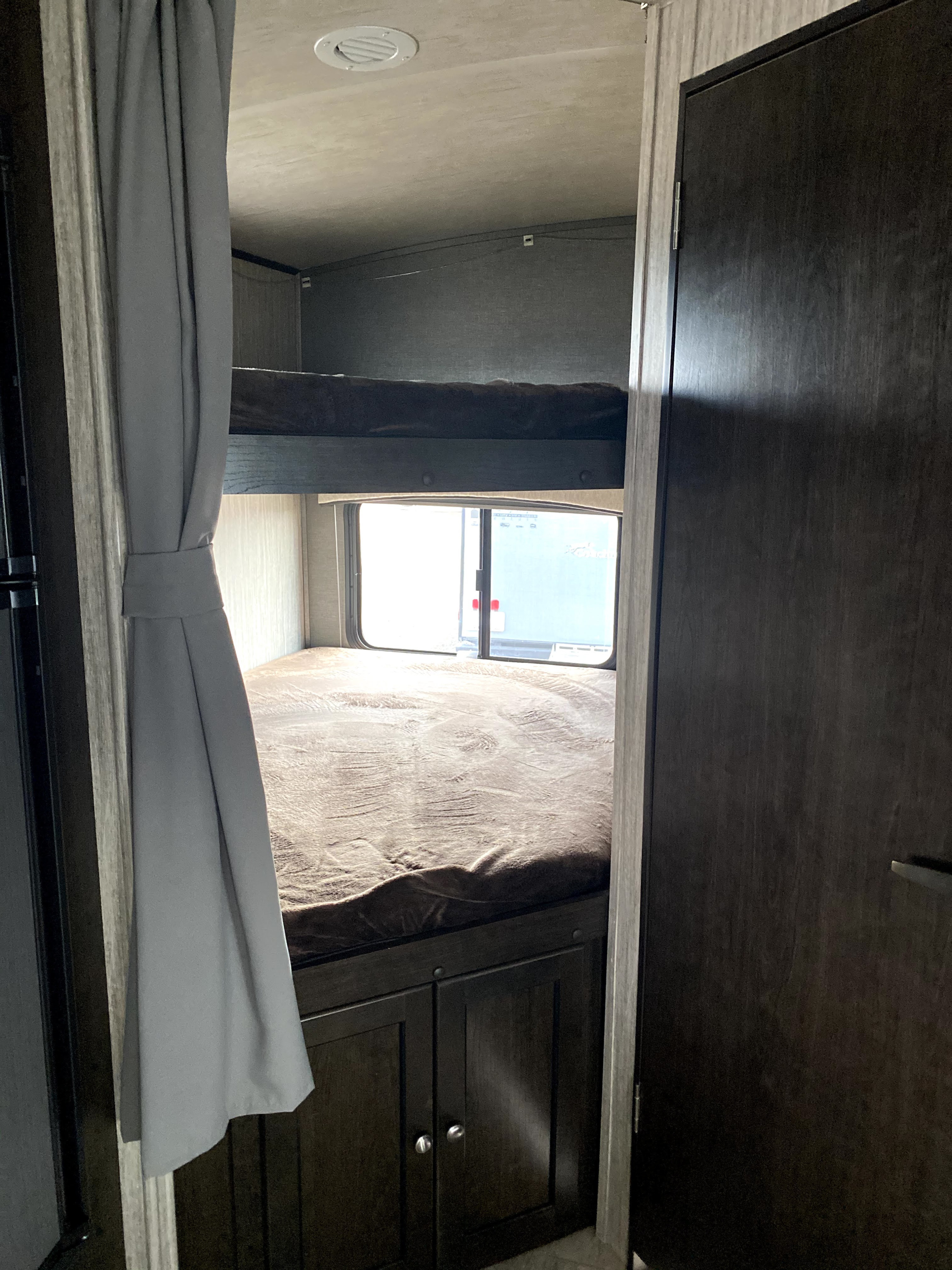Cozy RV rental interior with stacked bunk beds, a window, and storage cabinets, ready for your road trip.. Cruiser RV Shadow Cruiser 2019