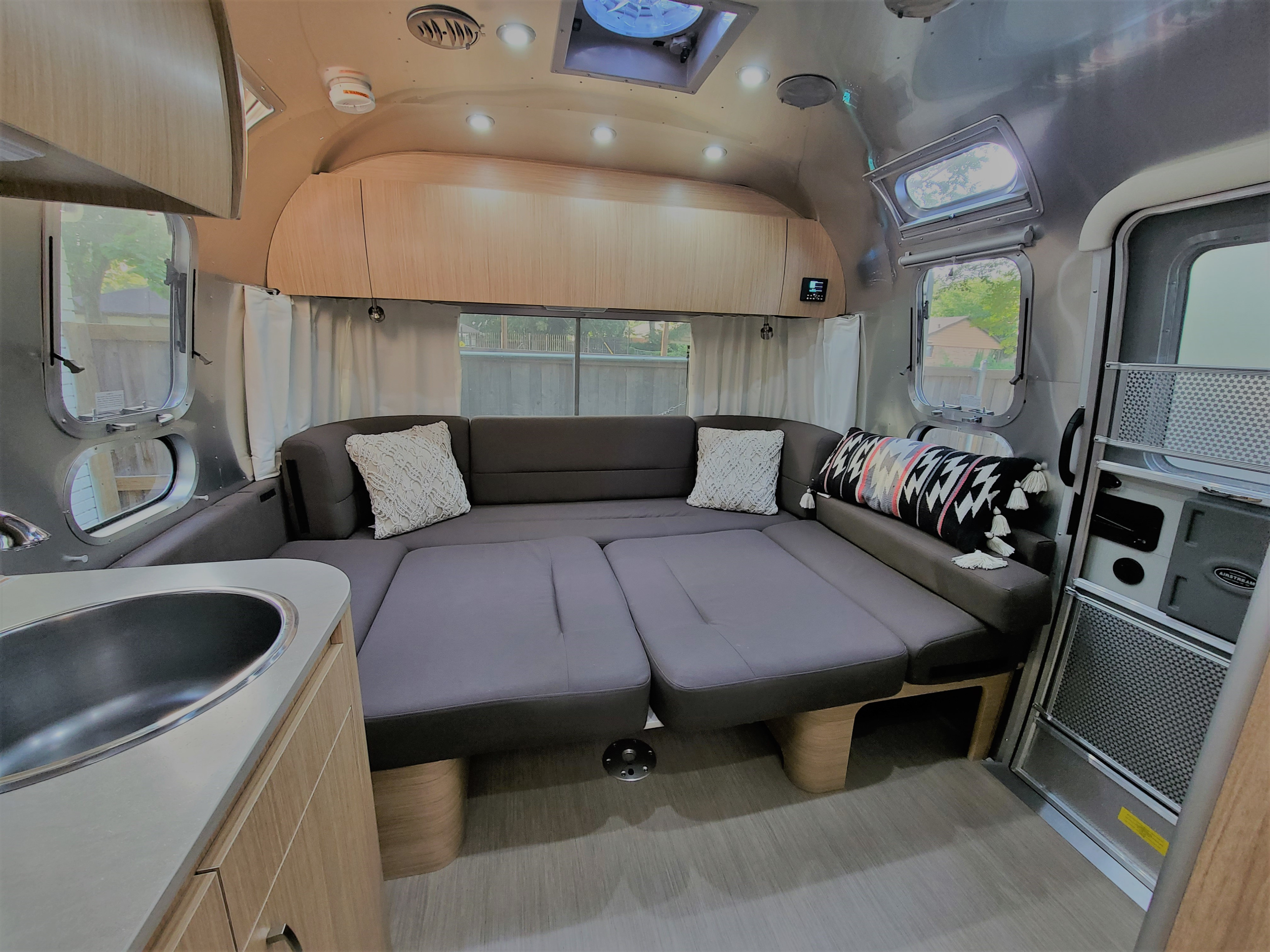 Discover this modern Airstream RV rental interior: spacious living area, convertible sofa bed, sleek kitchen, and bright windows.. Airstream Flying Cloud 2020