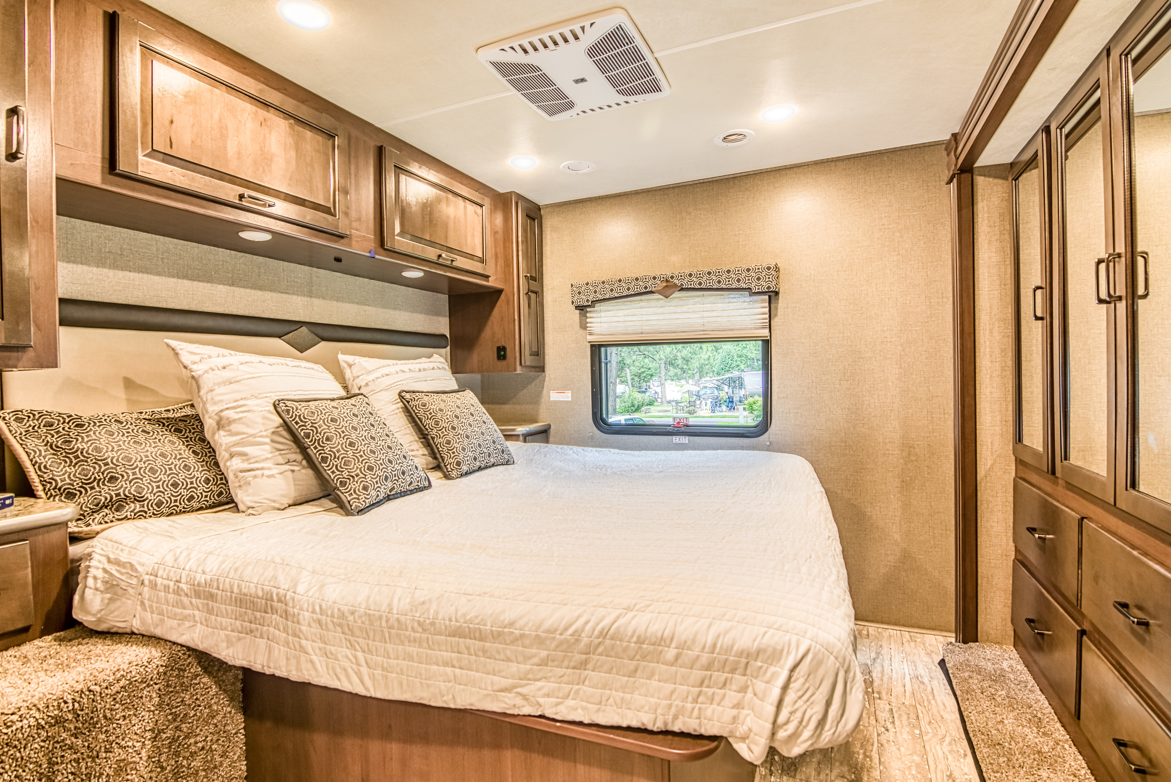 Explore a cozy RV rental bedroom featuring a queen bed, abundant overhead cabinets, a window, and a mirrored wardrobe.. Other Hurricane 2020