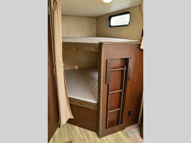 Inside an RV rental, showing comfortable bunk beds with a window and a folding ladder for easy access.. Forest River Cherokee 2019