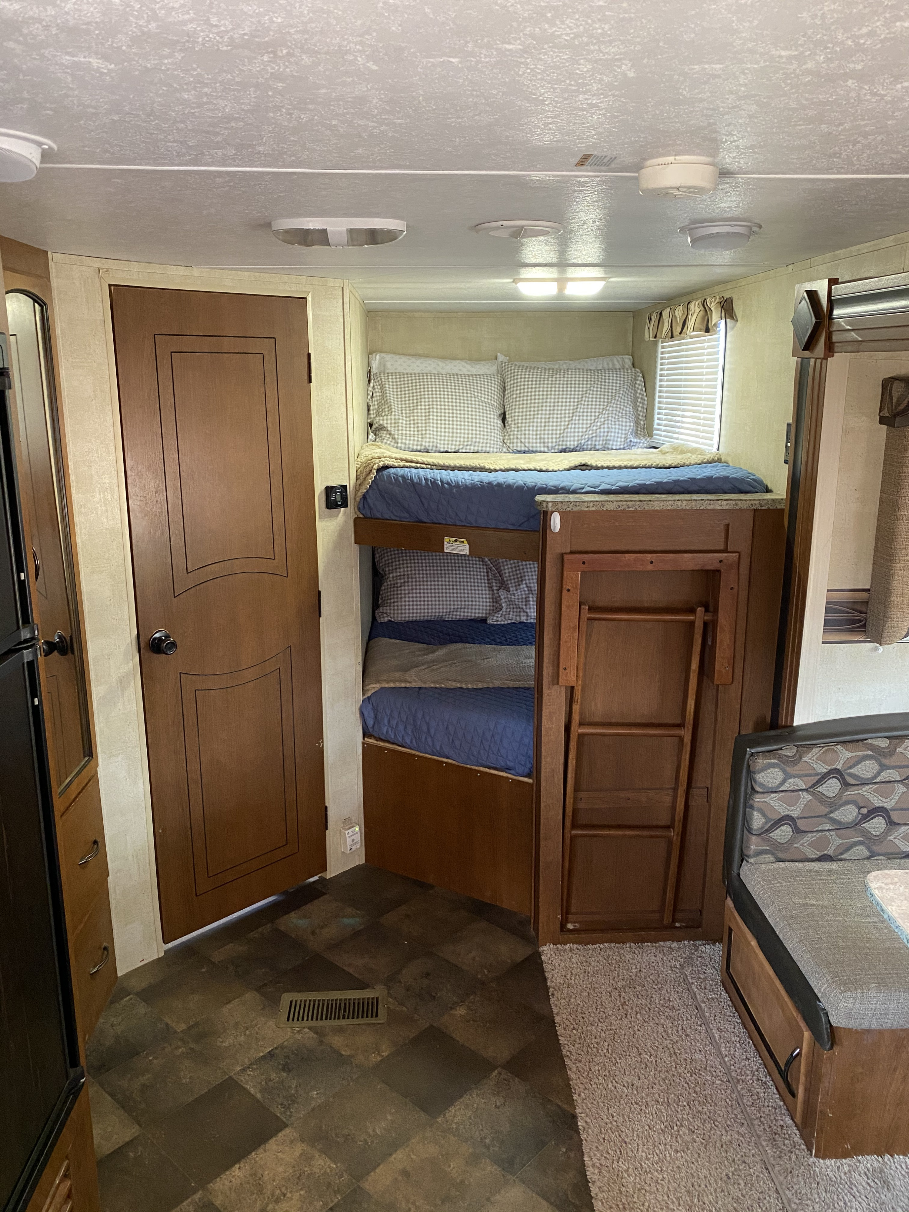 Spacious RV rental interior featuring bunk beds, a dining booth, and part of the kitchen near the door.. Keystone Springdale 2014