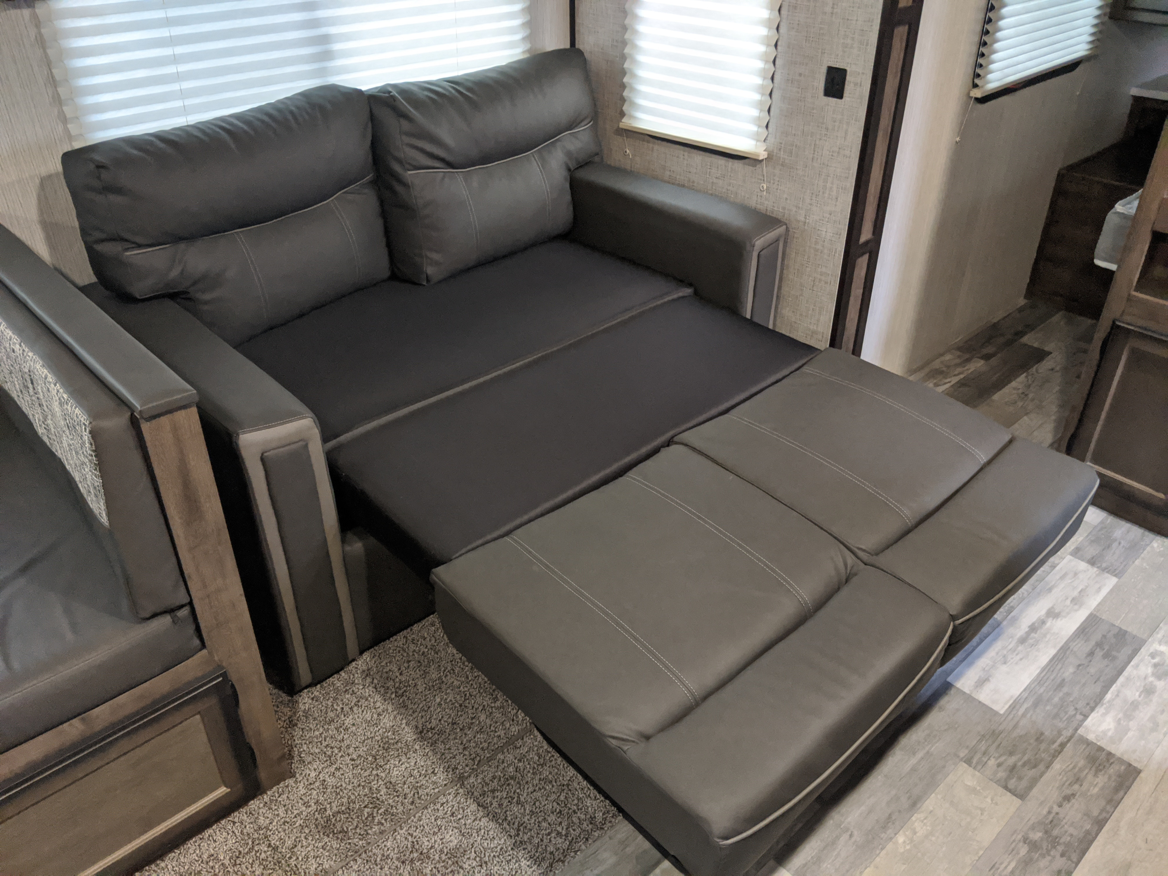 Modern RV rental interior featuring a gray convertible sofa-bed, partially extended for lounging or sleeping.. Heartland Mallard 2020