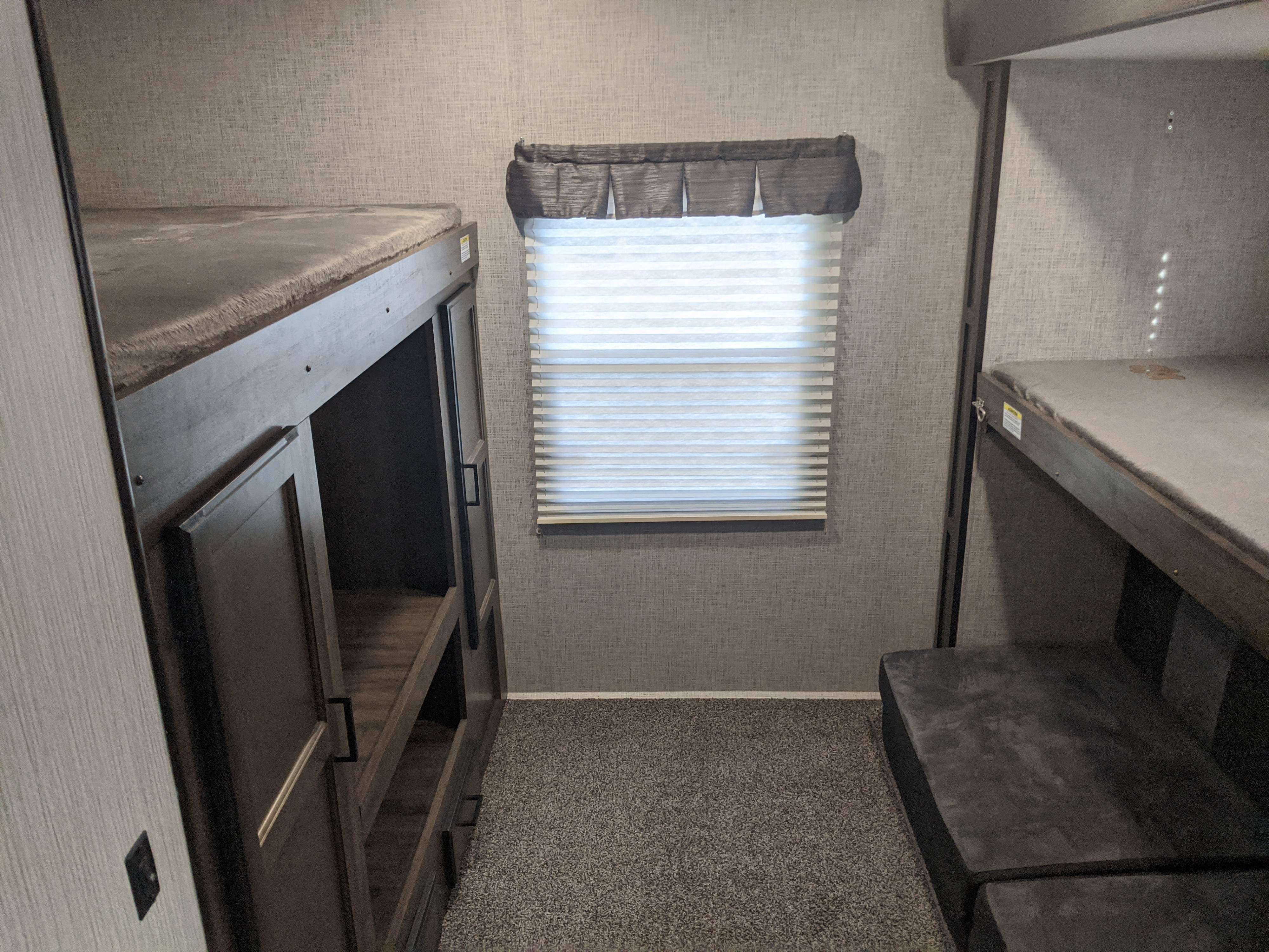 RV rental bunkhouse: twin beds, window with blinds, and built-in storage on soft carpet.. Heartland Mallard 2020