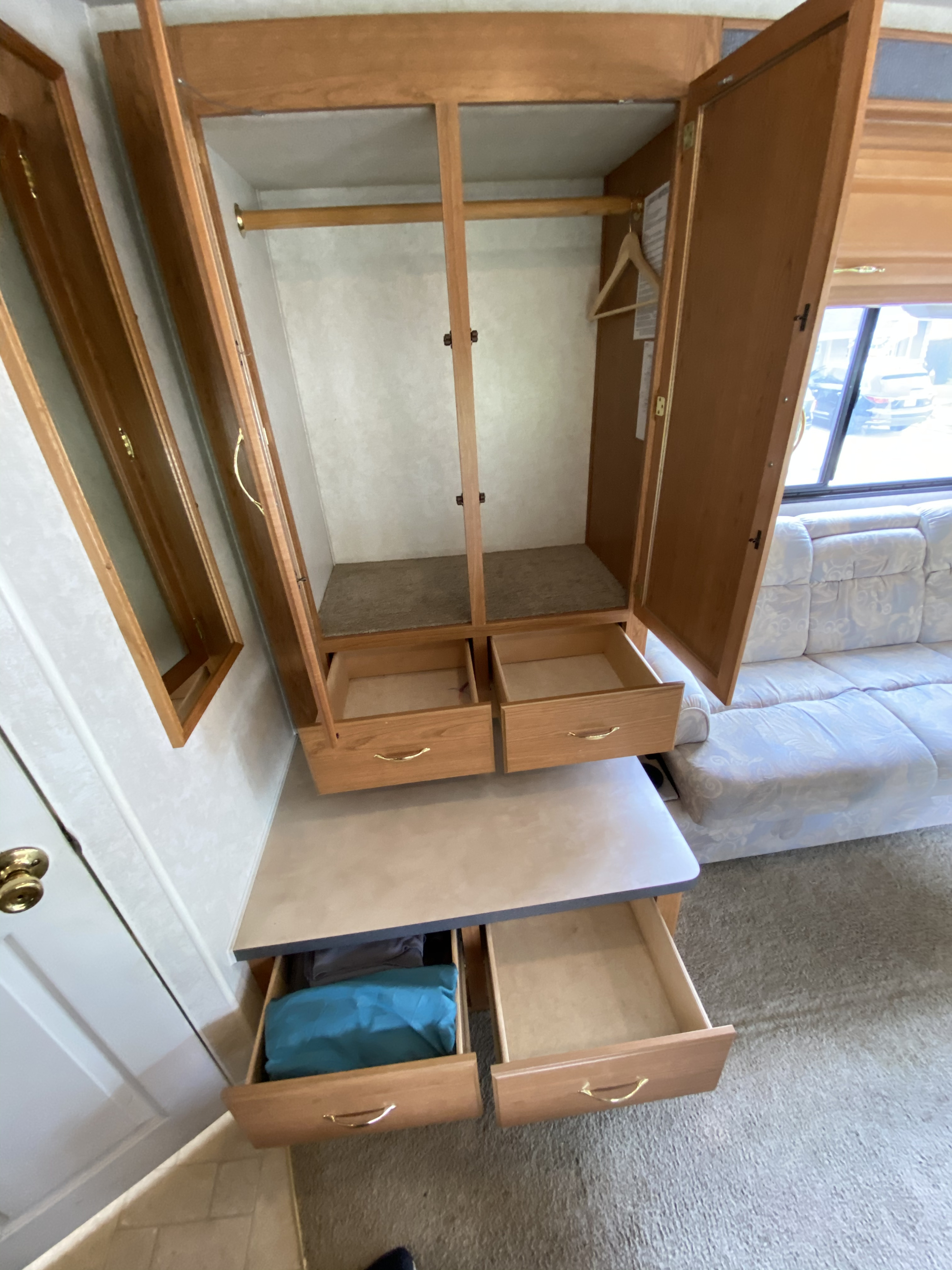 Efficient RV rental storage: A compact wardrobe with two upper and two lower open drawers, plus a hanging bar, for travel essentials.. Fleetwood Tioga 2003