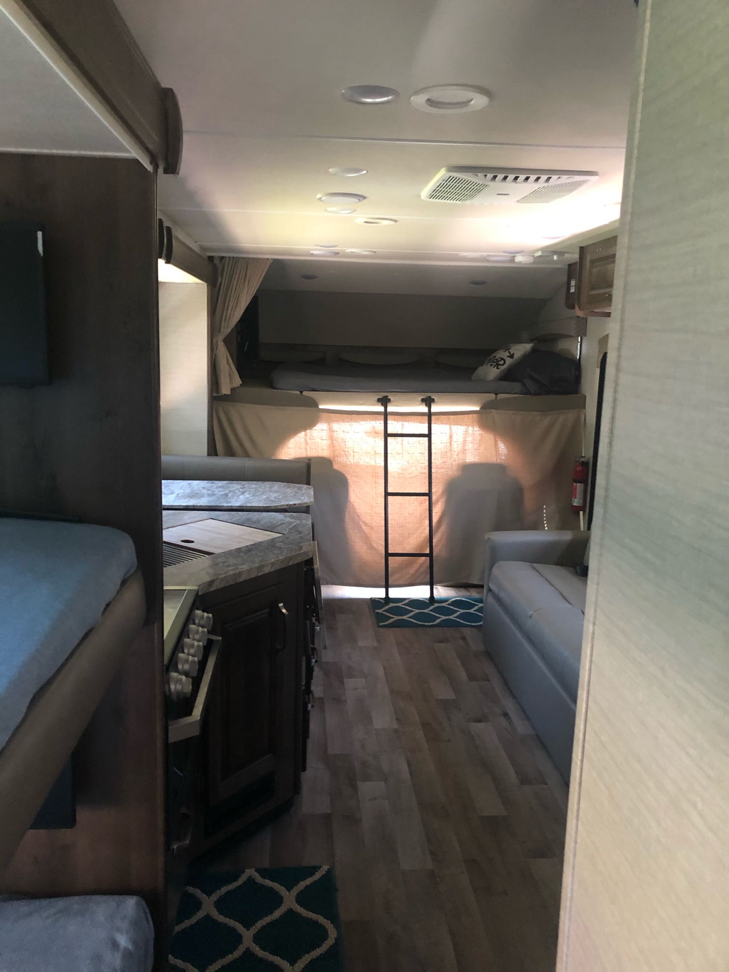 Spacious RV rental interior featuring a cozy cab-over bed, kitchen, and living area with comfortable seating.. Jayco Greyhawk 2019