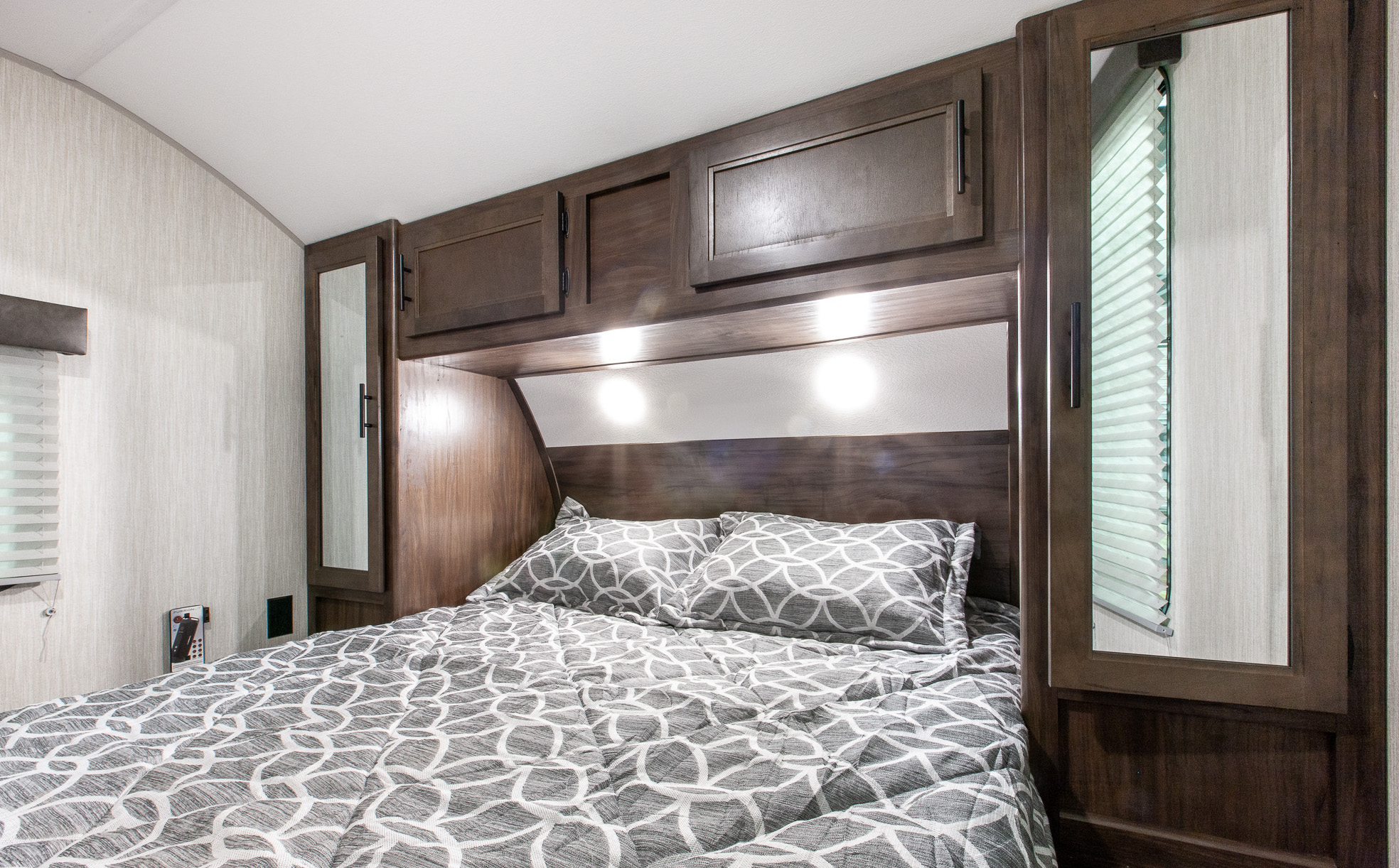 Comfortable RV rental bedroom with patterned bedding, overhead cabinets, and reading lights, ideal for your next trip.. Forest River Cherokee Grey Wolf 2020