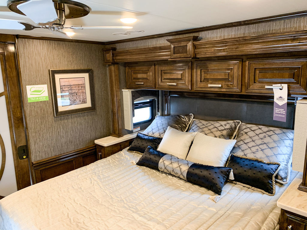 Spacious RV rental bedroom with comfortable bed, elegant wooden cabinets, and a ceiling fan, offering a cozy travel retreat.. Thor Motor Coach Tuscany 2019