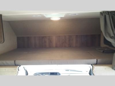 This RV rental features a comfortable cab-over bunk sleeping area with a mattress, wood trim, and privacy curtains.. Nexus Triumph 23T 2020