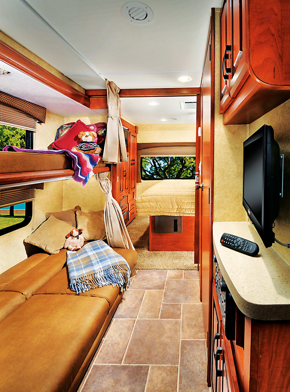 Comfortable rv rental interior featuring bunk beds, a master bed, and cozy living area. Ideal for family adventures.. Forest River Sunseeker LE 2015