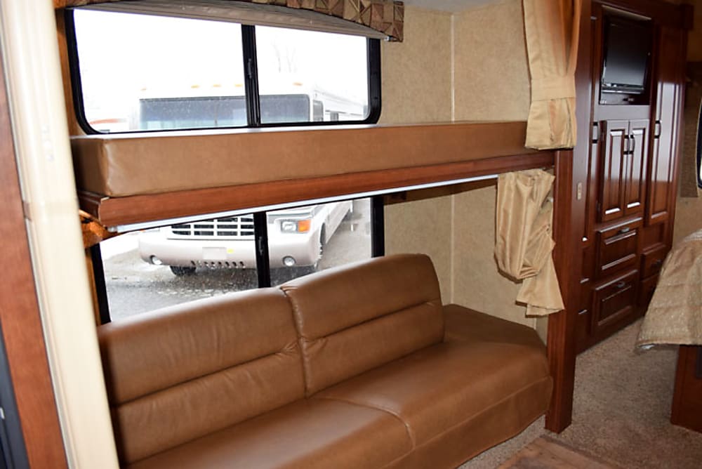 RV rental interior: Features comfy bunk beds above a leather sofa, with built-in storage and TV. Spacious living area.. Forest River Sunseeker LE 2015