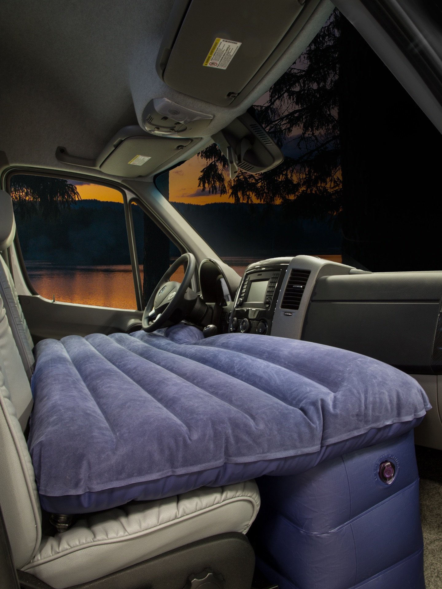 RV rental van cabin with a blue air mattress installed for cozy camping, offering a scenic lake and sunset view.. Roadtrek Agile Ss 2014