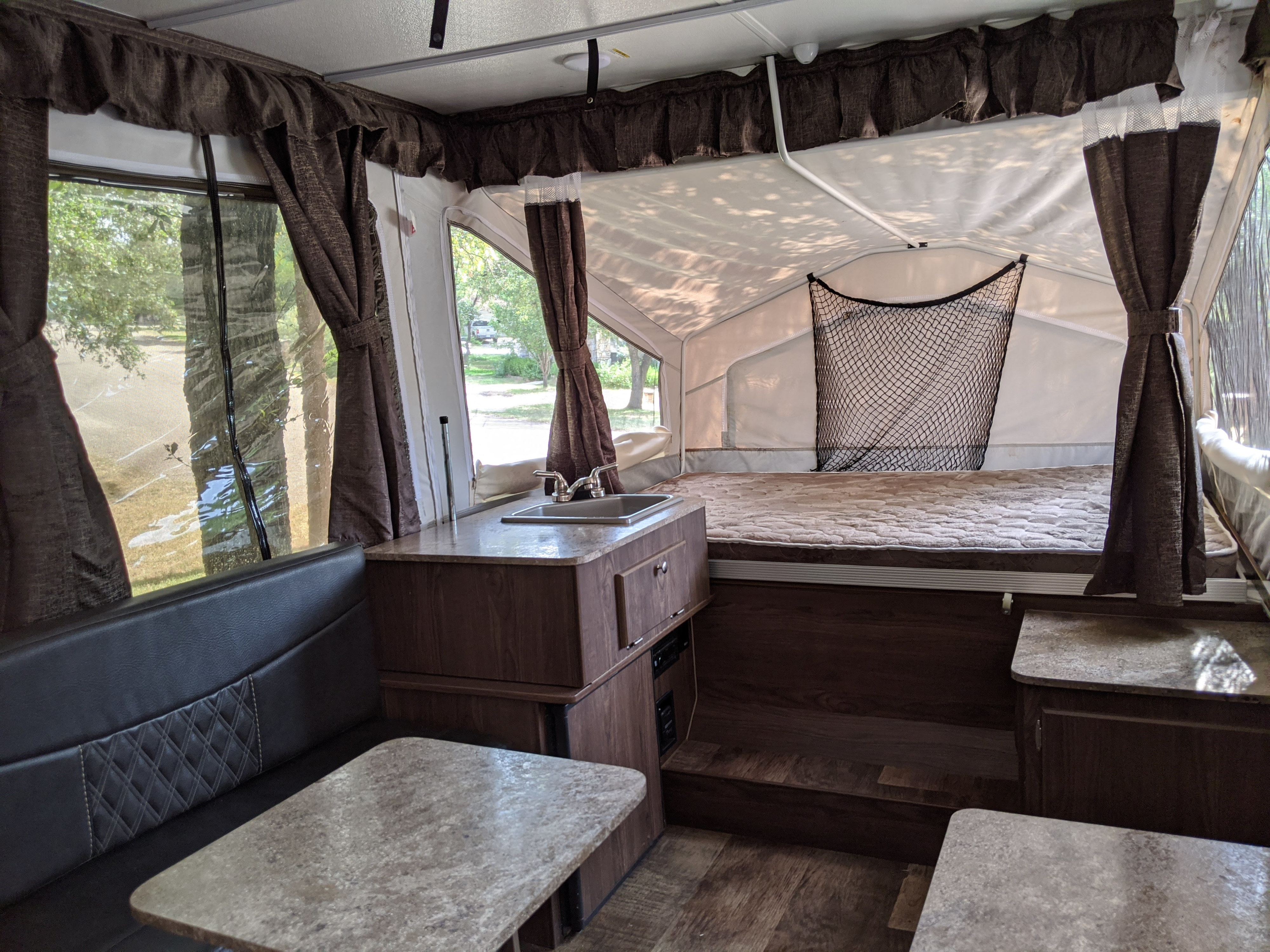 An inviting pop-up camper interior, ready for your next RV rental adventure. Features comfortable dinette, functional kitchen, and dual bed areas.. Forest River Rockwood 2018