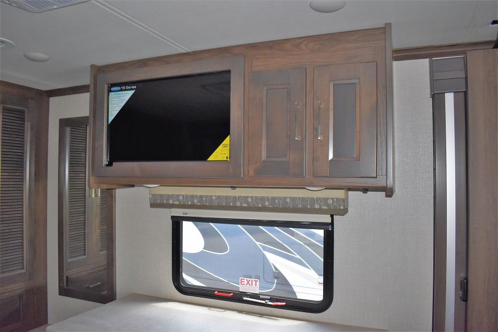 Modern RV rental interior features an entertainment center with TV, storage cabinets, and a scenic window view.. Coachmen Sportscoach 2020