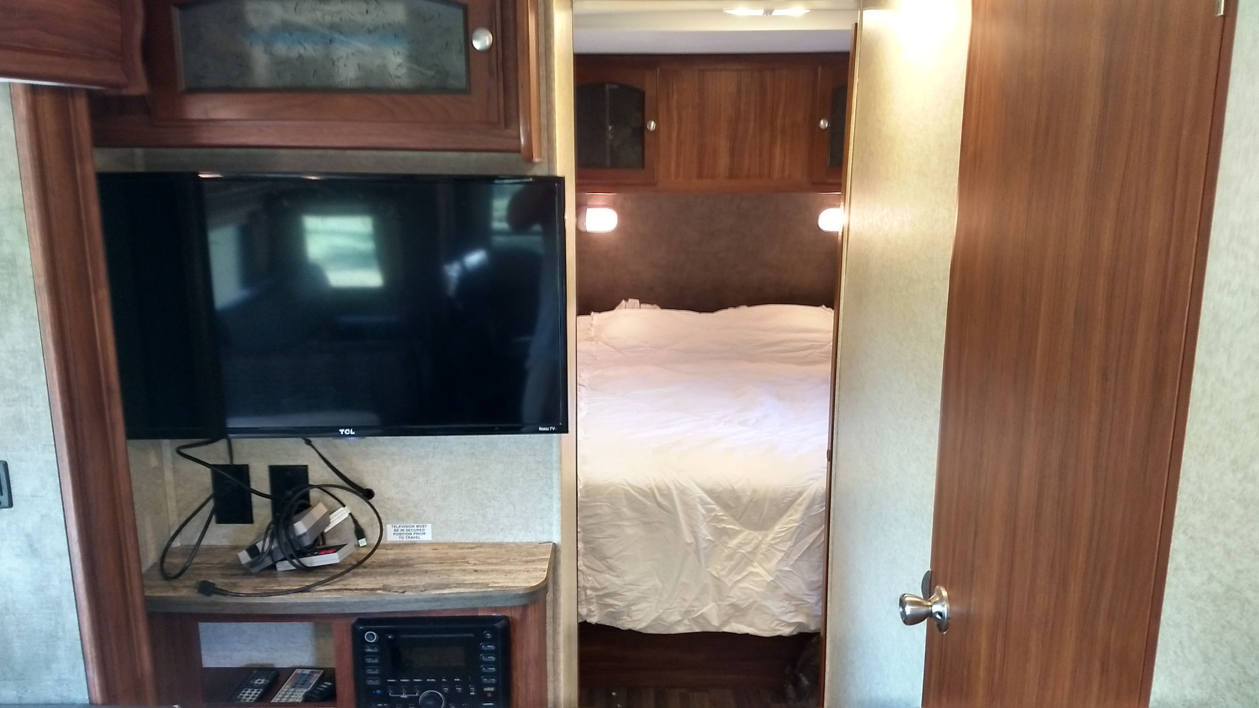 Inside an RV rental: a compact living space featuring a TV entertainment center and a peek into the bedroom.. Heartland North Trail 2015
