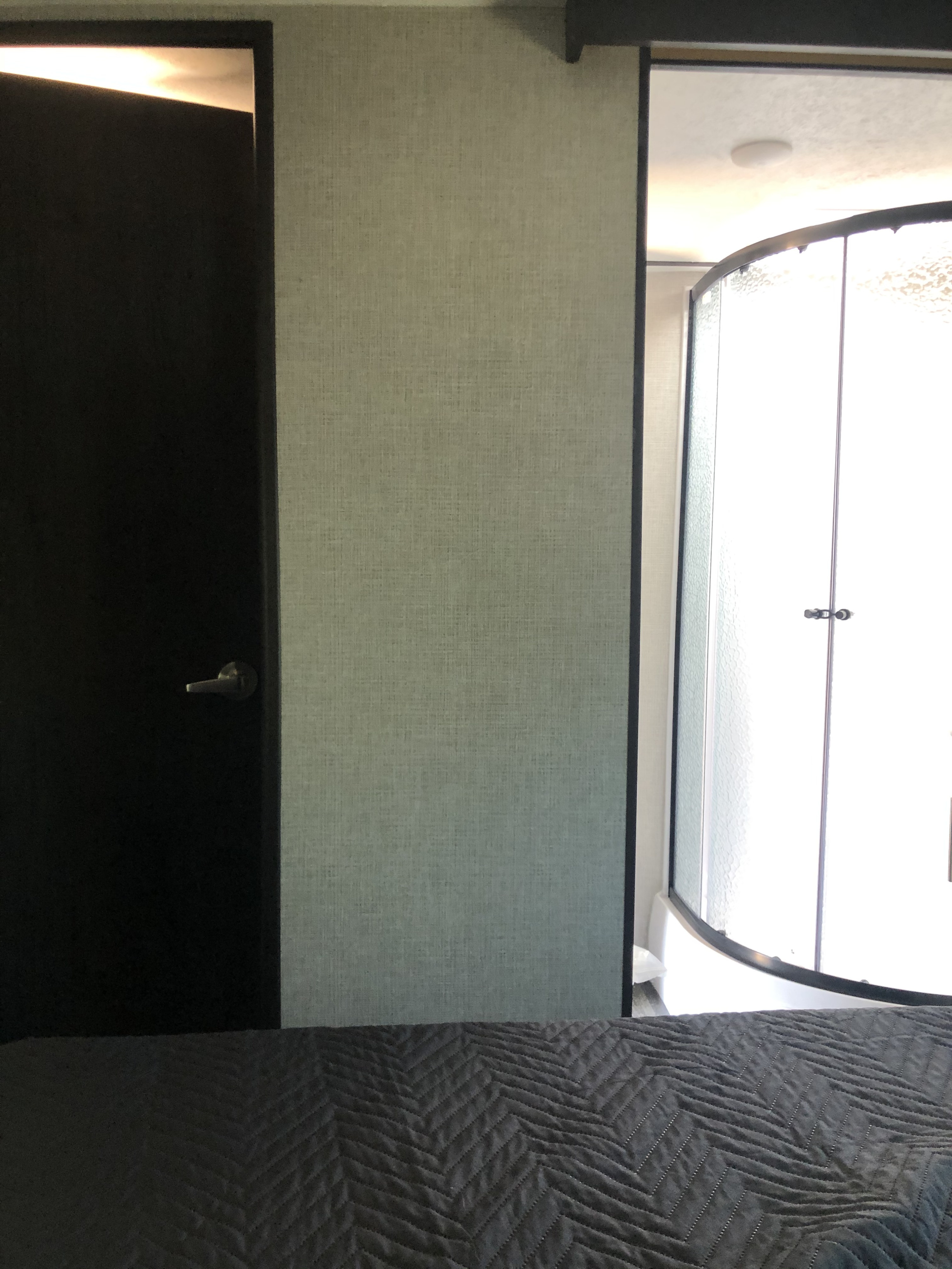 RV rental: View from bed showing a dark door, textured wall, and bright curved glass shower enclosure.. Keystone Bullet 2021