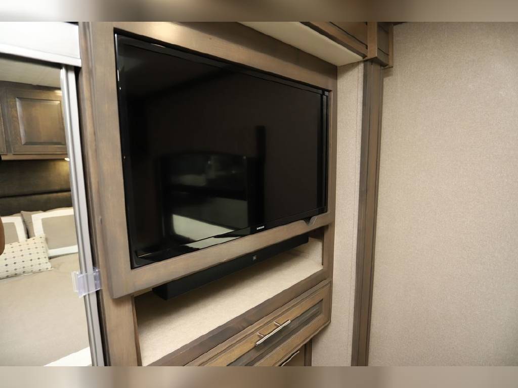 RV rental interior: wall-mounted TV with soundbar, storage below, next to bedroom entrance for comfort.. Dynamax Corp Dx3 2020