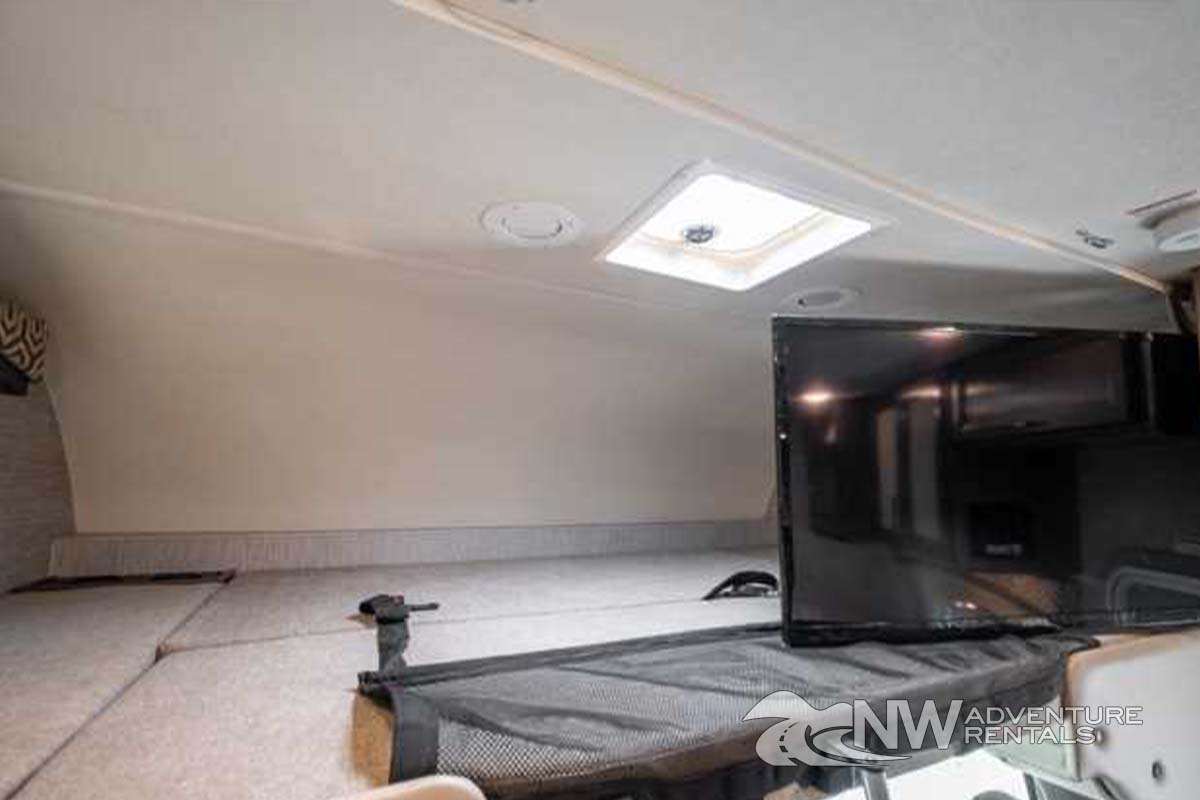 Explore this RV rental's comfortable cab-over bunk, featuring a flat-screen TV & ceiling skylight for your travels.. Thor Motor Coach Chateau 2021