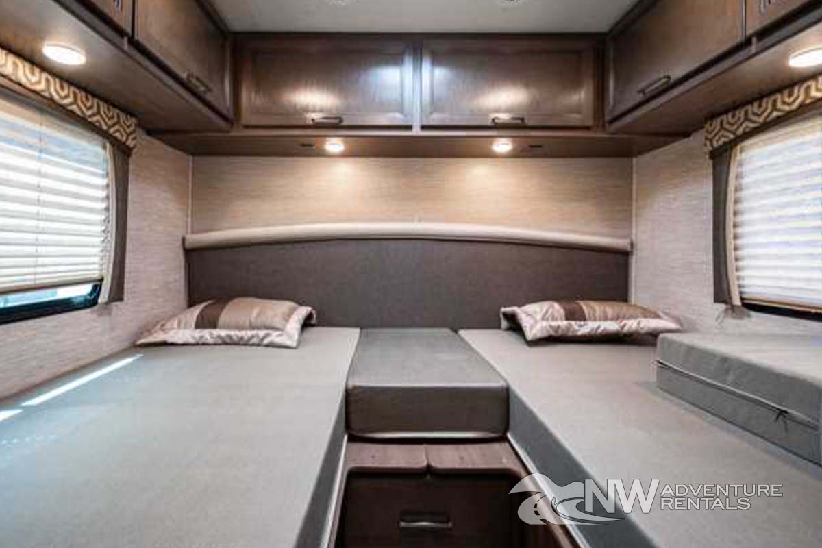 Spacious RV rental bedroom featuring two comfortable beds, overhead storage, and large windows for natural light.. Thor Motor Coach Chateau 2021