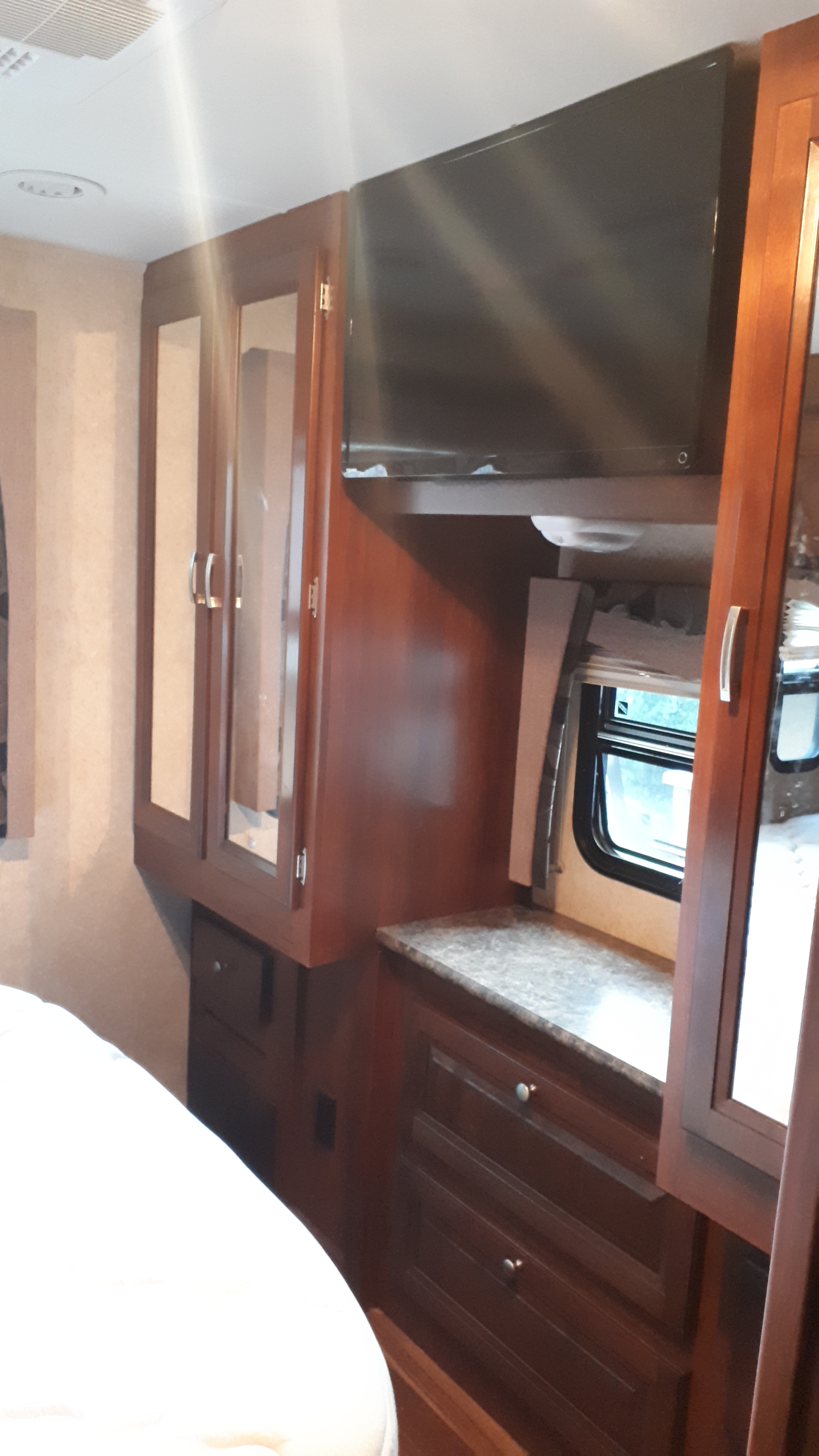Compact rv rental interior with wood cabinets, TV, and a bed. Provides essential comfort for your travel adventures.. Forest River Georgetown 2014