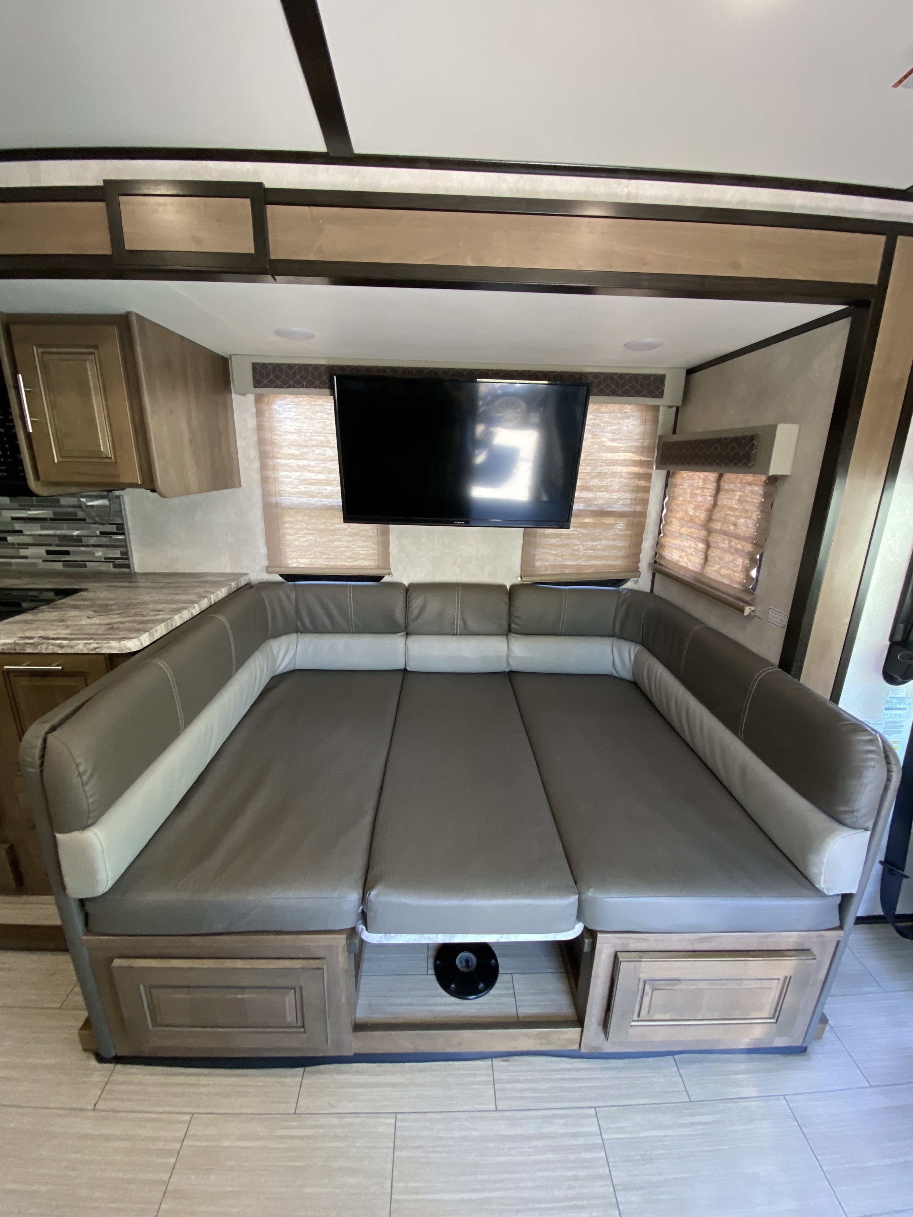 This RV rental interior features a versatile U-shaped dinette converting to a bed, a TV, and a compact kitchen.. Forest River FR3 2021