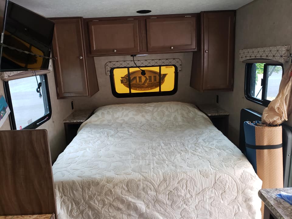 Step into this comfortable RV rental bedroom, featuring a large bed, overhead cabinets, and a prominent "Viking" window shade.. Forest River Viking 2017