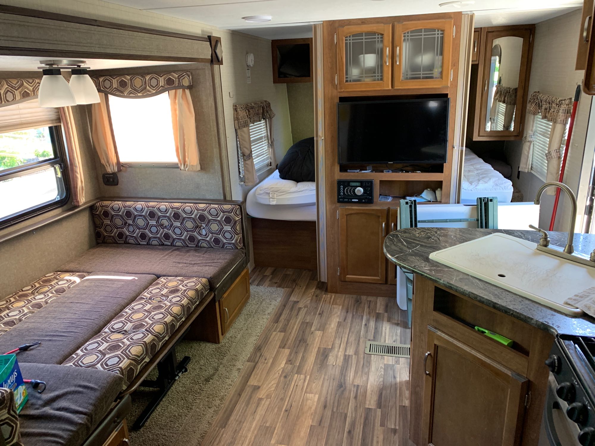 RV rental interior: living area with convertible sofa-bed, compact kitchen, and private bedroom with bed.. Keystone Springdale 2017