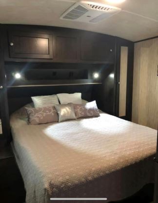 Inside an RV rental: a cozy bedroom featuring a comfortable bed, pillows, and overhead storage with lights.. Cruiser Rv Corp Shadow Cruiser 2018