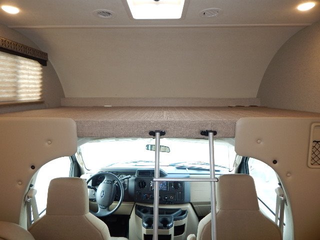 Inside an RV rental: view towards the front with a large overhead bunk, access ladder, and vehicle cockpit.. Other Other 2020