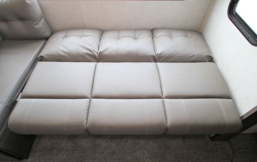 Light gray RV rental sofa easily converts to a bed. Features tufted back cushions & stitched seating for comfort.. Forest River Wildwood 2021
