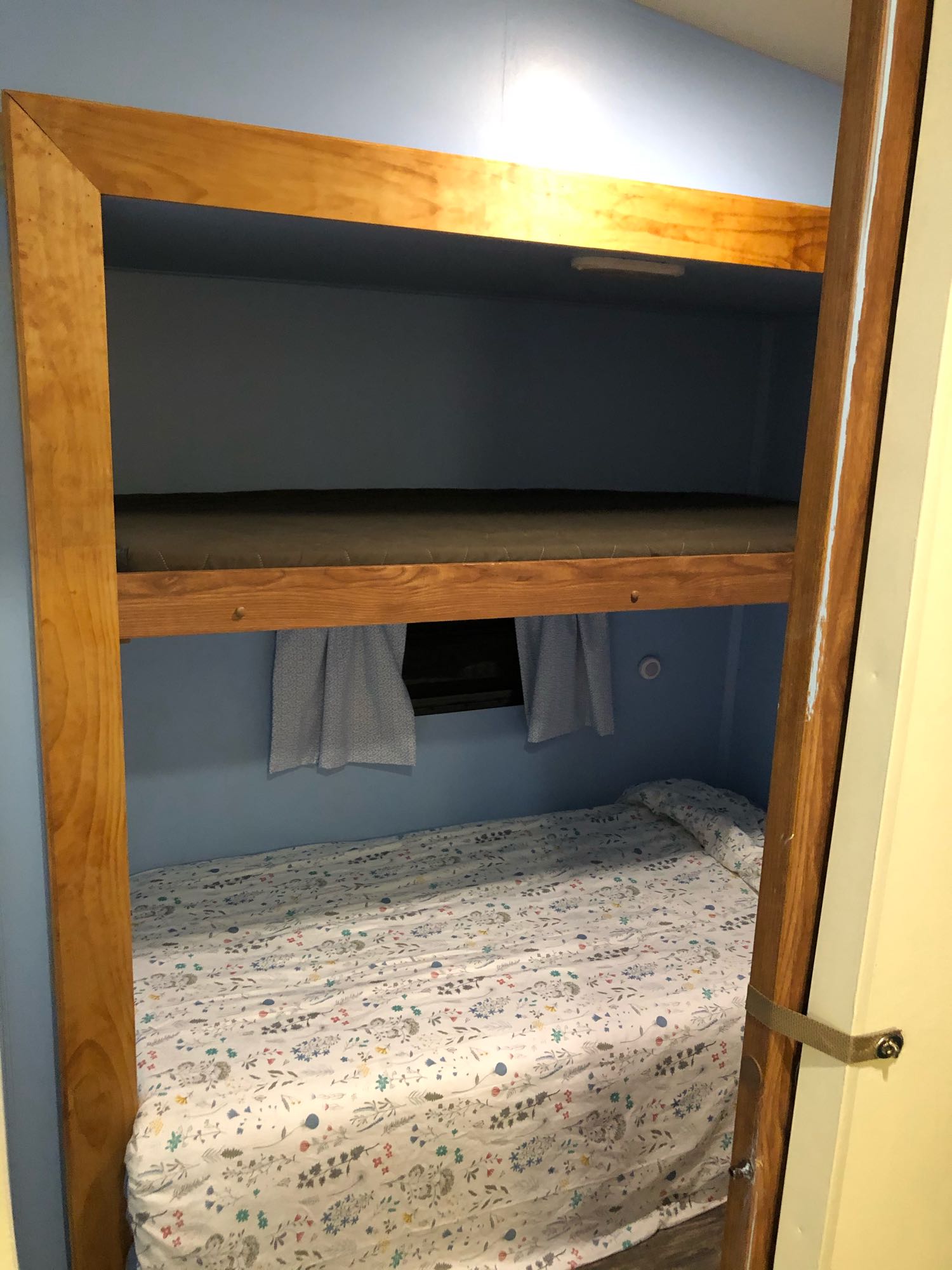 Two bunk beds with wooden frames in an RV rental. Light blue walls, patterned lower bunk, and a small window for a compact sleep space.. Forest River Flagstaff Classic Super Lite 2014