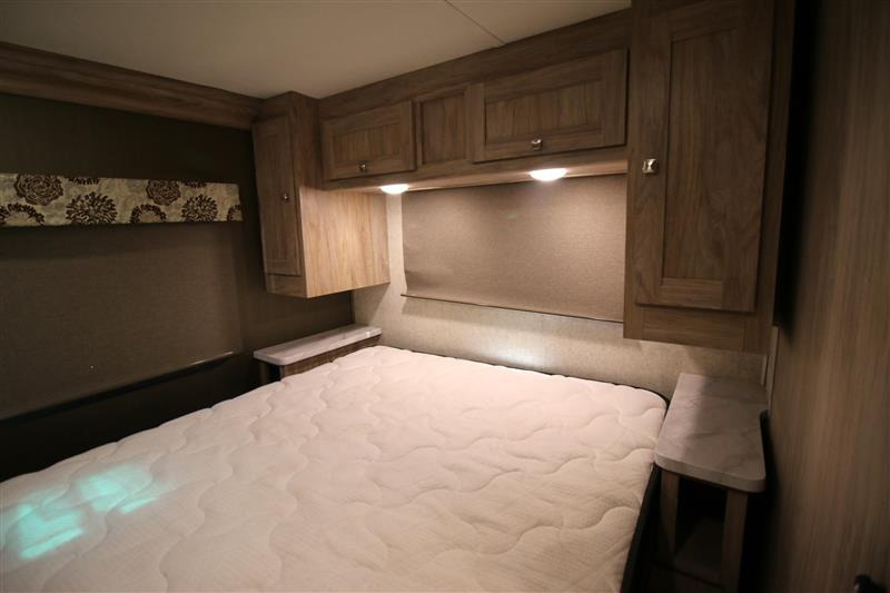 Comfortable RV rental bedroom with a double bed, wooden overhead cabinets, and soft lighting.. Forest River Forester 2020
