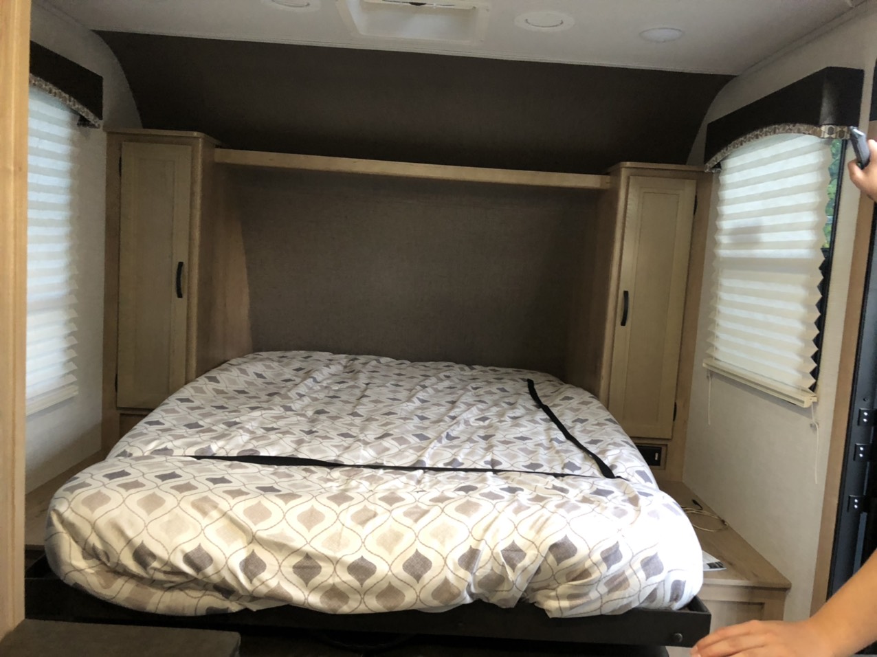 RV rental bedroom featuring a neatly made bed with patterned bedding, built-in side storage, and window blinds.. Winnebago Minnie Winnie 2021