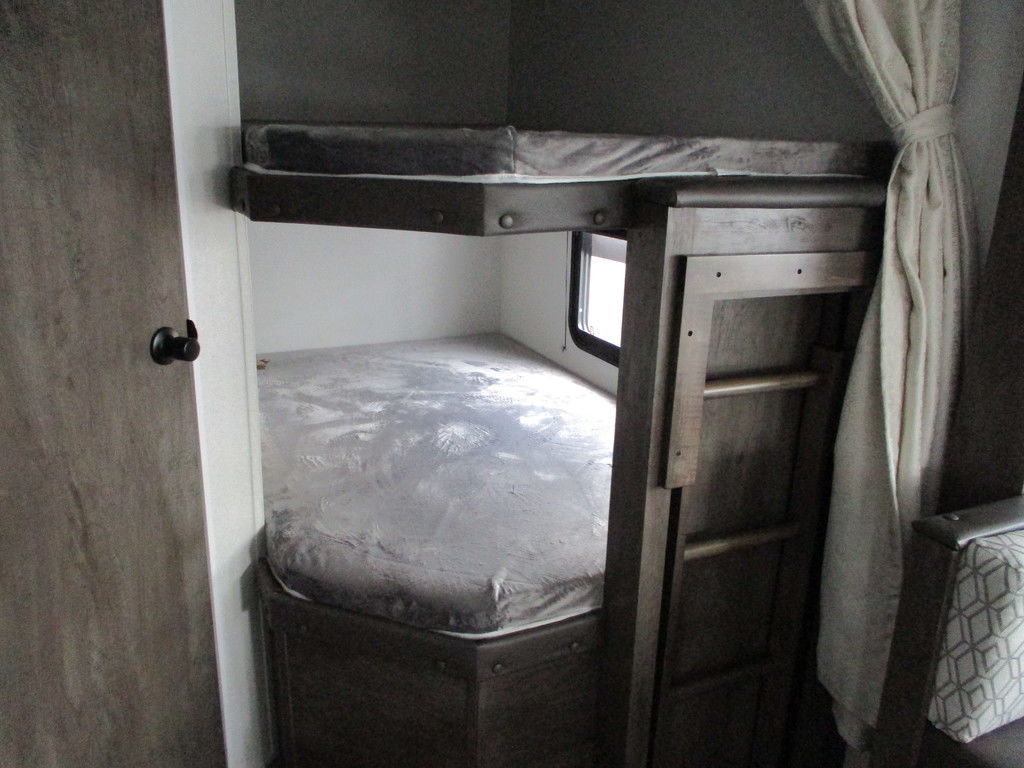 View of a compact **rv rental** interior, featuring two bunk beds, a ladder, and a window for sleeping.. Forest River Evo 2021